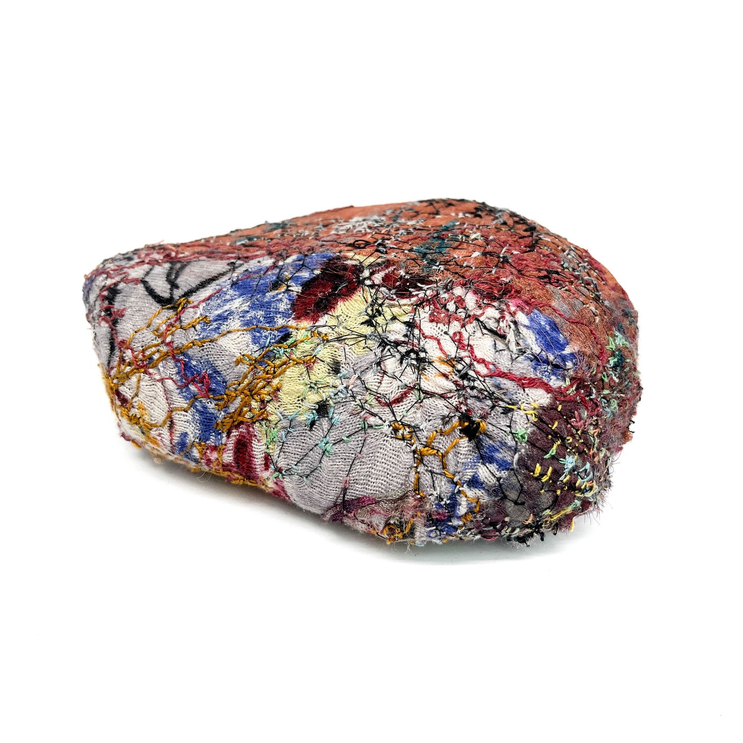 Textile art: a rock-like form densely covered in colorful threads and stitched patterns.