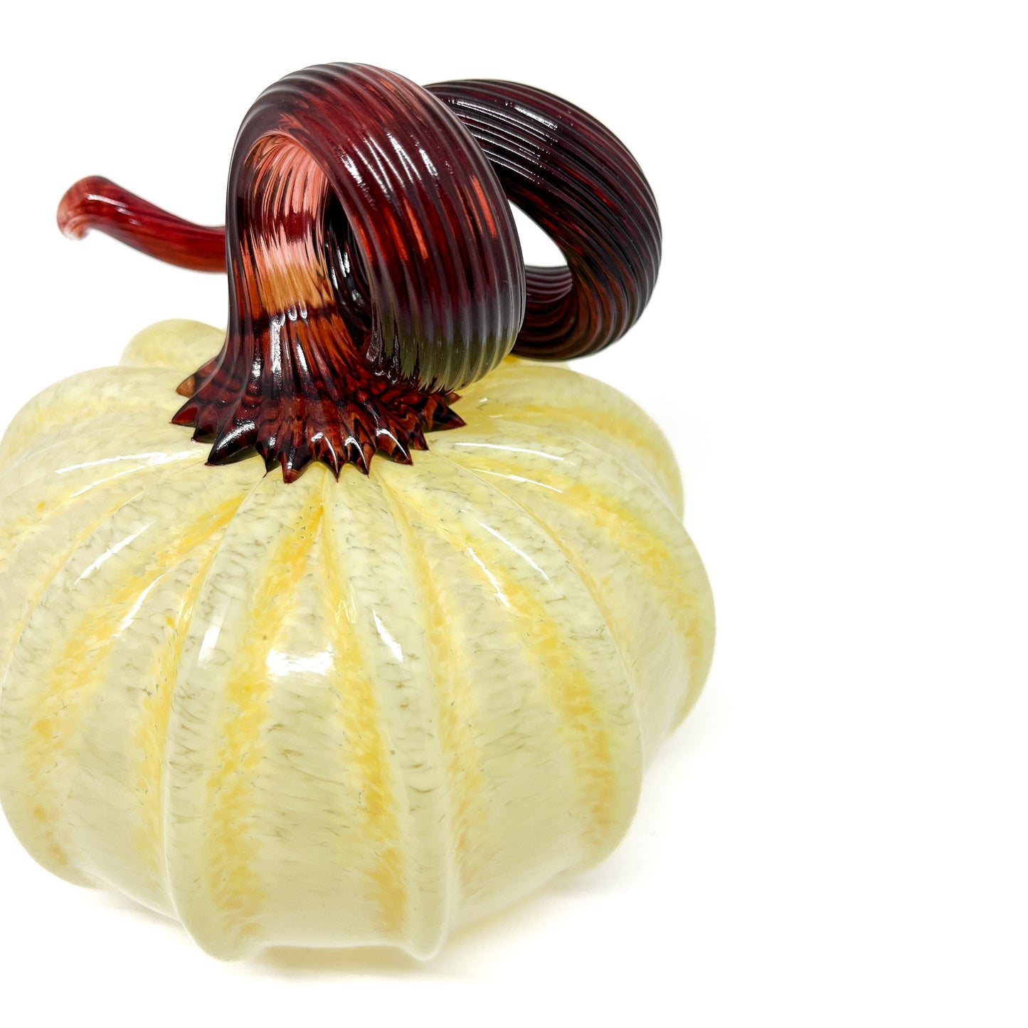 A pale yellow glass pumpkin with a curled, dark red glass stem.
