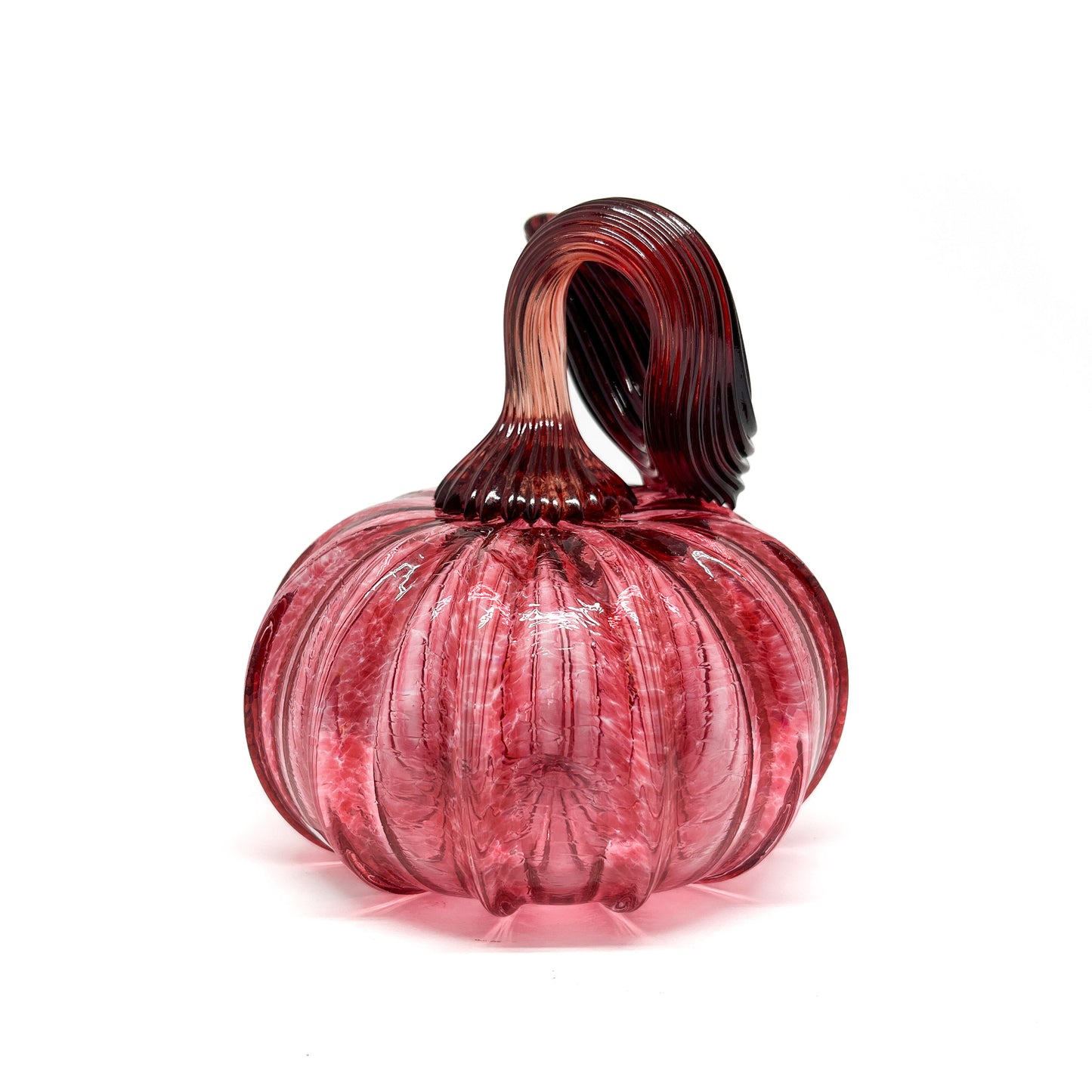 A pink glass pumpkin with a curled, dark red glass stem.
