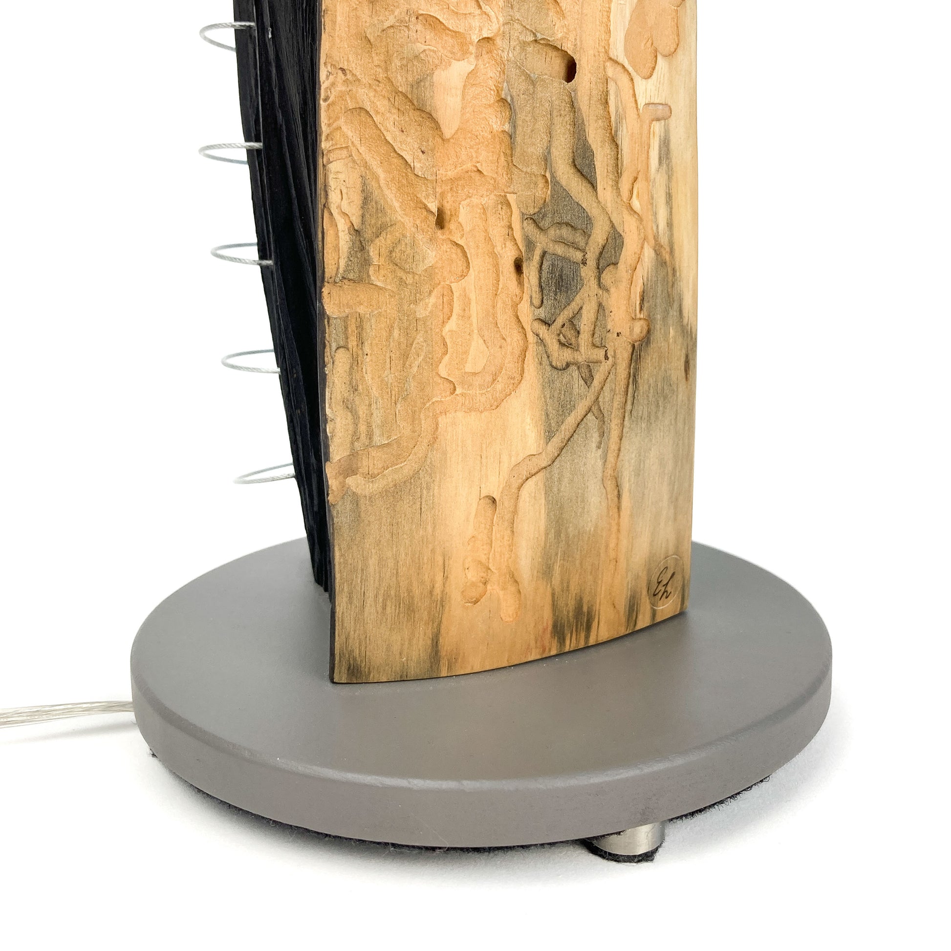 A lamp with a gray base and a wooden body with markings. Metal rings are attached to the side.