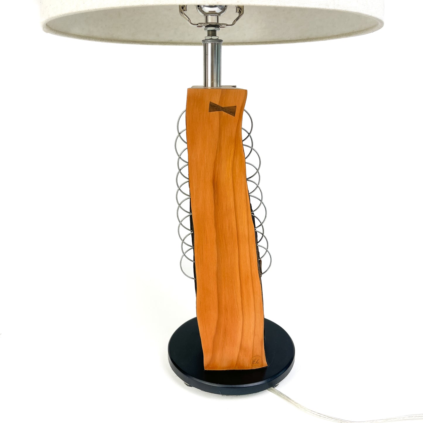 A table lamp with a light wood base, metal rings, white shade, and black round base.