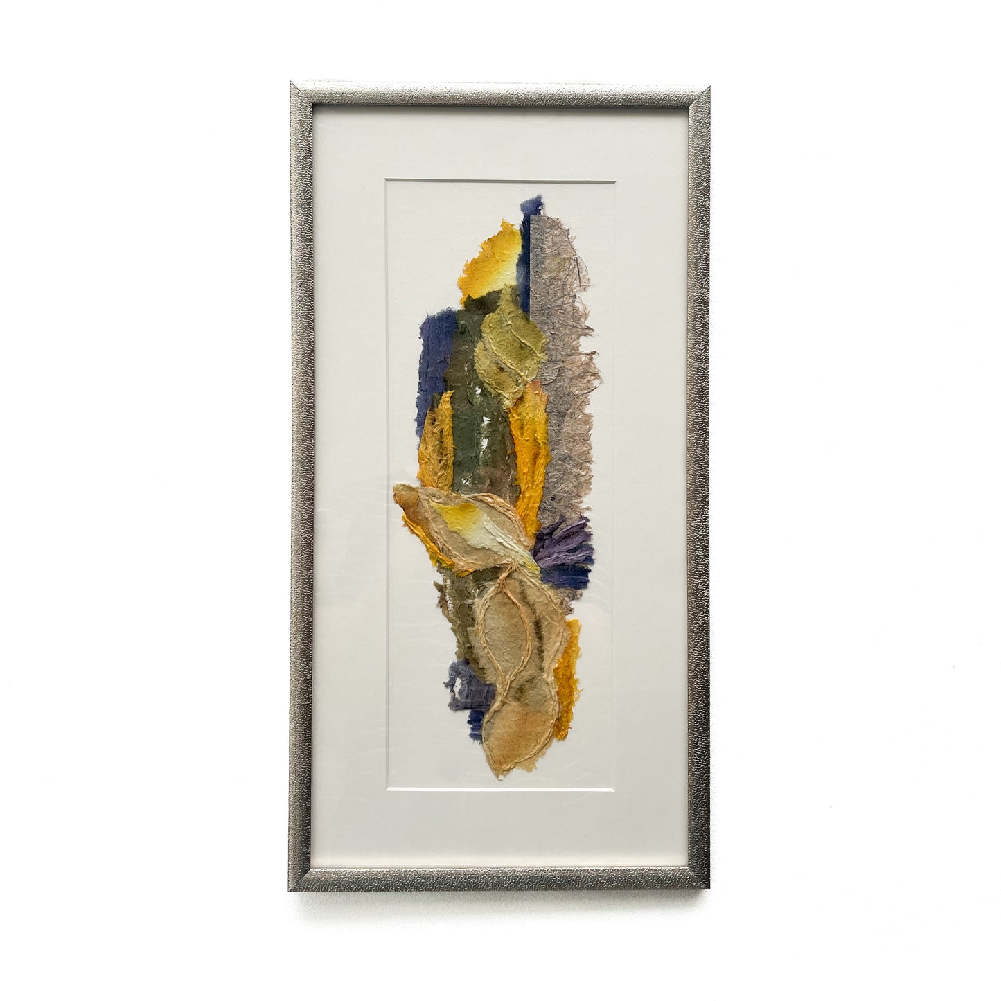 Framed abstract textile art with layered textures and blended hues of yellow, blue, green, brown, and gray.