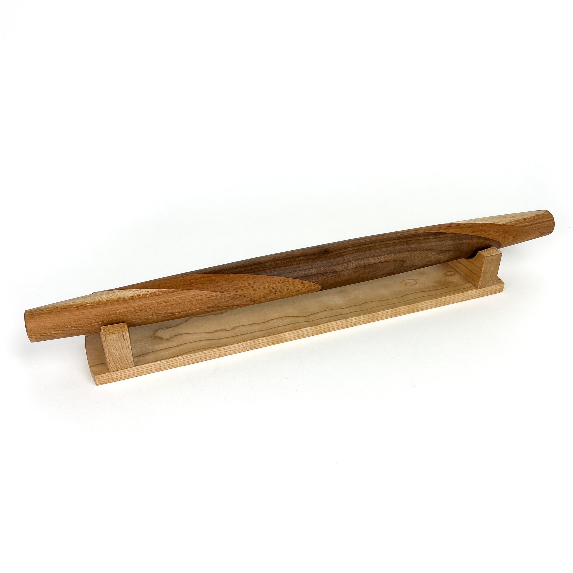 A wooden rolling pin with a unique design, resting on a wooden stand. The rolling pin has a smooth, polished finish.