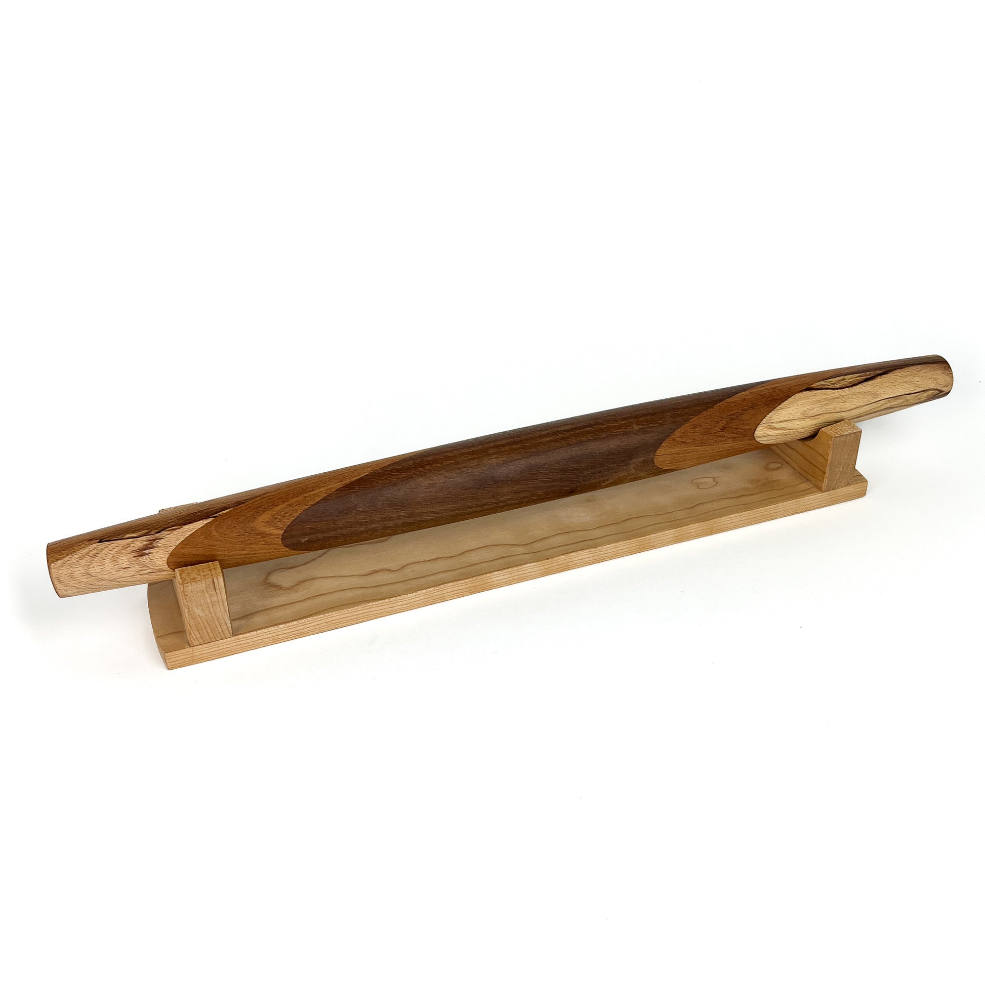 A wooden rolling pin with a unique design, resting on a wooden stand. The rolling pin has a smooth, polished finish.