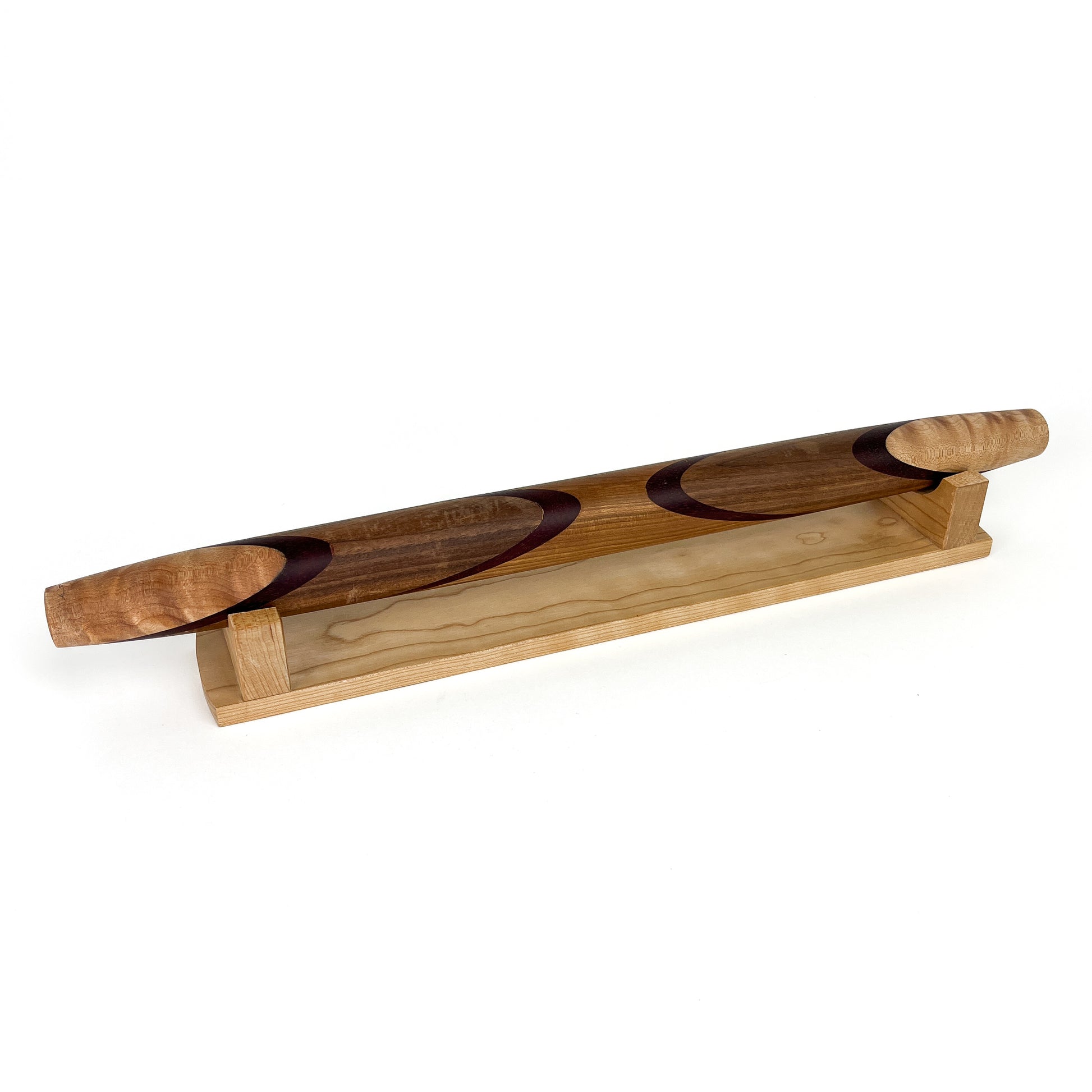 A wooden rolling pin with a unique design, resting on a wooden stand. The rolling pin has a smooth, polished finish.