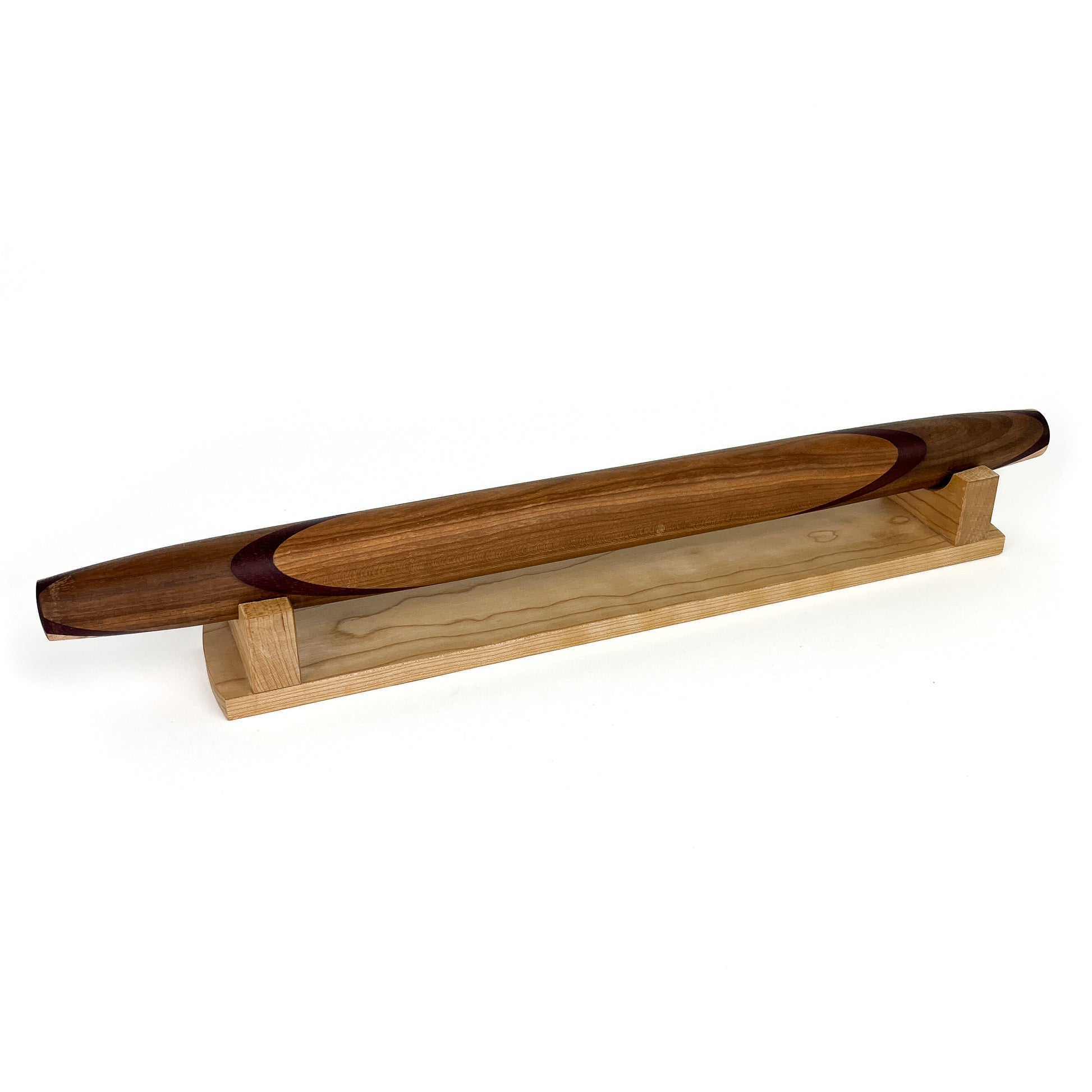 A wooden rolling pin with a unique design, resting on a wooden stand. The rolling pin has a smooth, polished finish.
