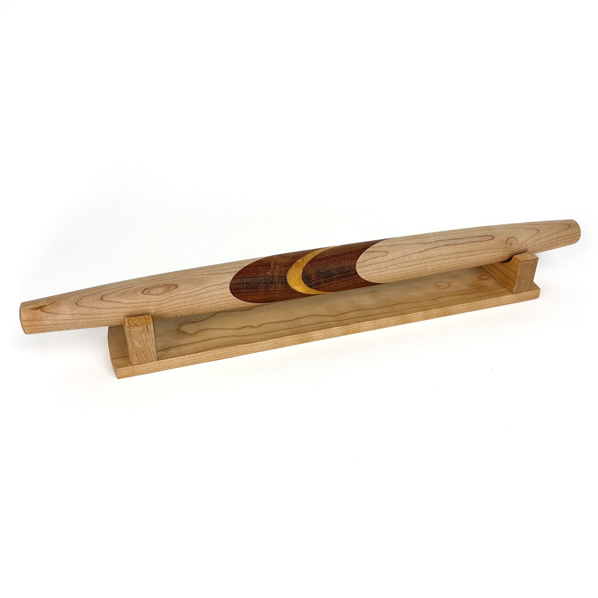 A wooden French rolling pin with a crescent moon inlay, resting on a wooden stand. The pin has a smooth, polished finish.