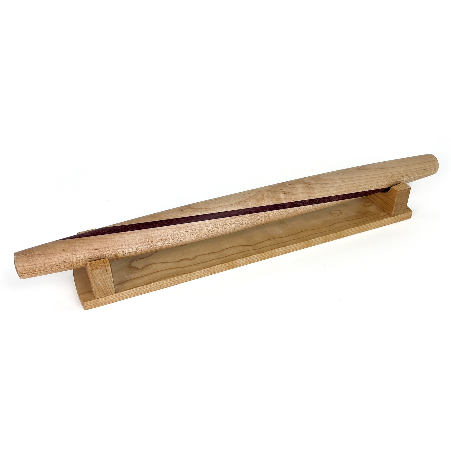 A light-colored wooden French rolling pin with a thin dark stripe, resting on a wooden stand. The pin has a smooth, polished finish.