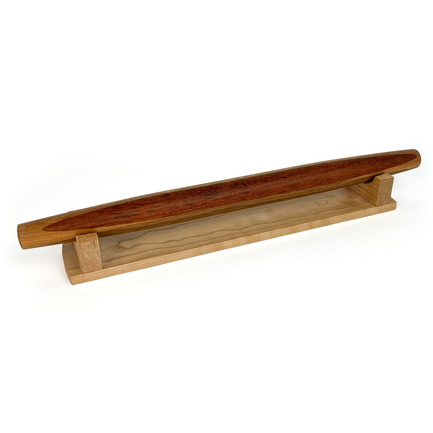 A French rolling pin made of Jatoba wood, resting on a Sugar Maple stand. The pin has a smooth, polished finish.