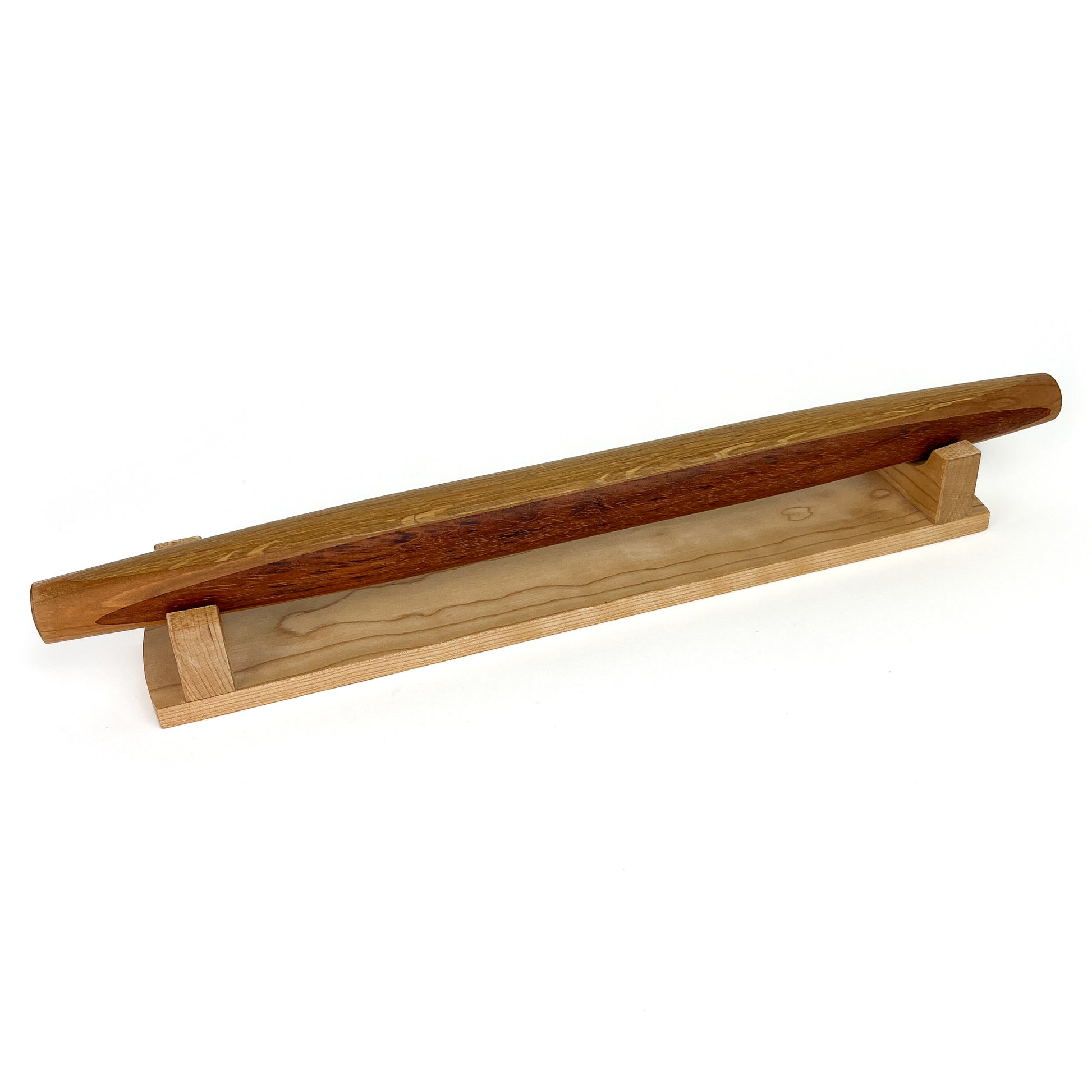 A French rolling pin made of Jatoba wood, resting on a Sugar Maple stand. The pin has a smooth, polished finish.