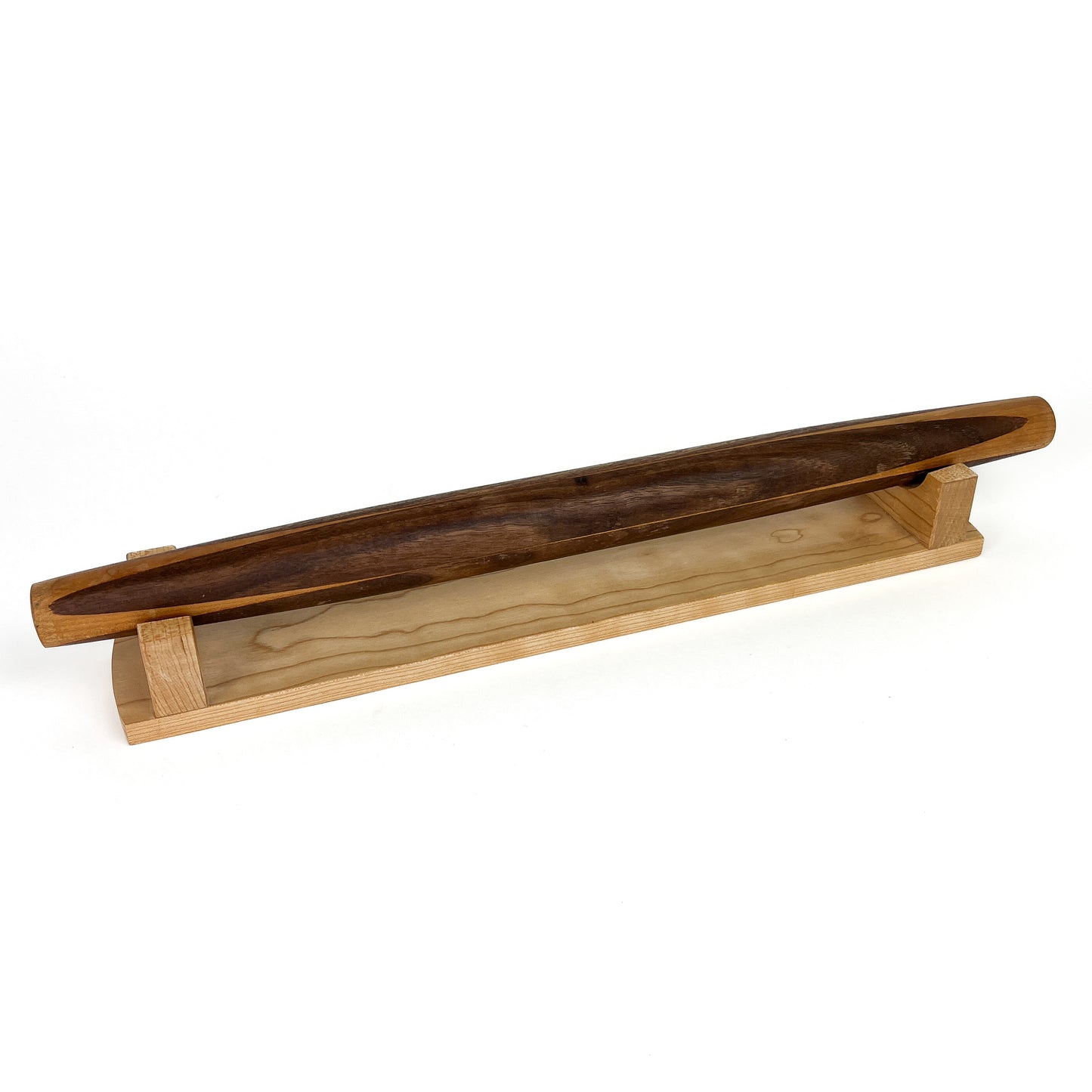 A French rolling pin made of Black Walnut wood, resting on a Sugar Maple stand. The pin has a smooth, polished finish.