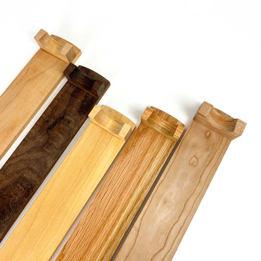 Five wooden French rolling pin stands made of different types of wood, angled diagonally. Each stand has carved supports for the rolling pin.