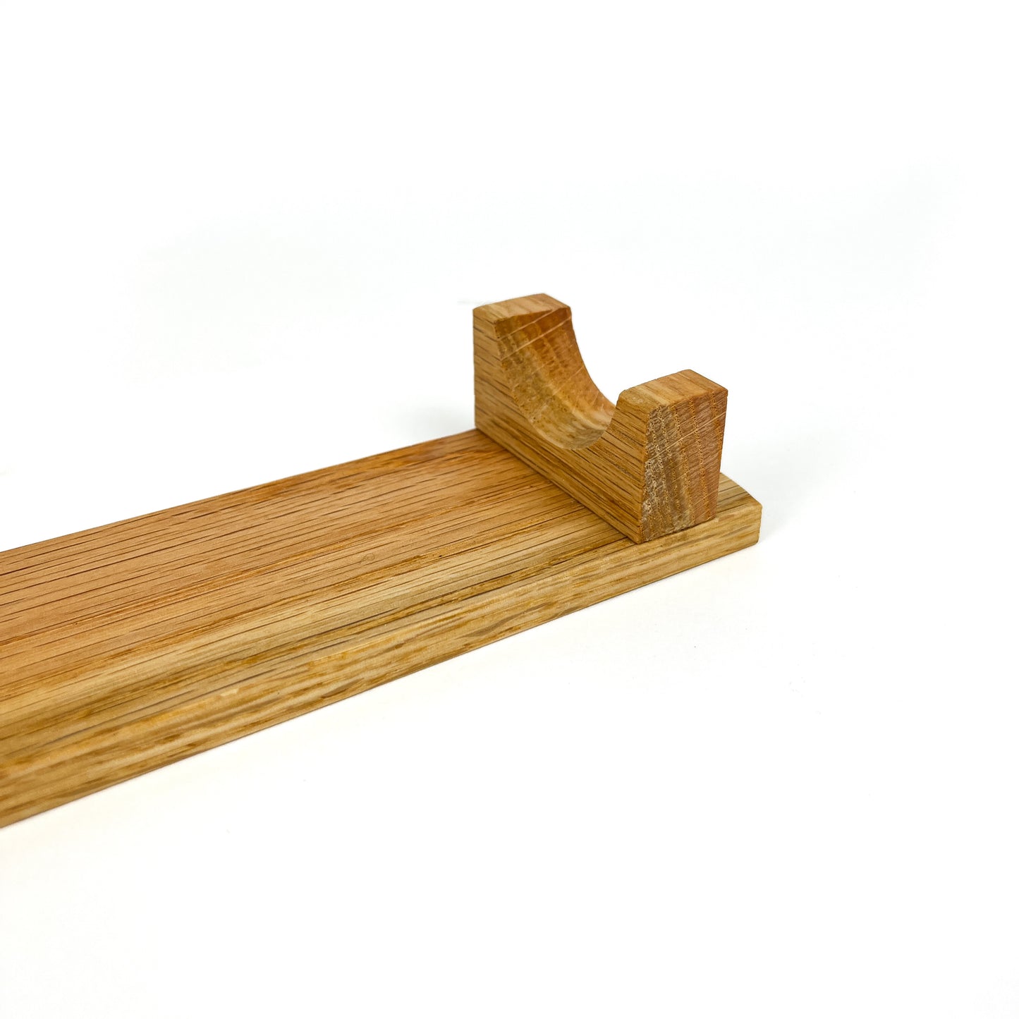A close-up of a light wooden French rolling pin stand, showing one of the carved supports. The stand has a visible wood grain.