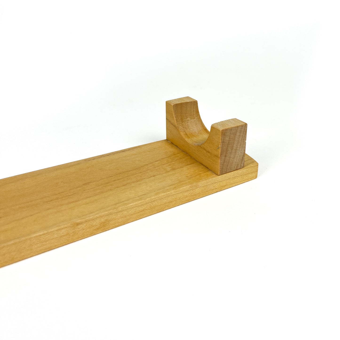 A close-up of a light wooden French rolling pin stand, showing one of the carved supports. The stand has a visible wood grain.