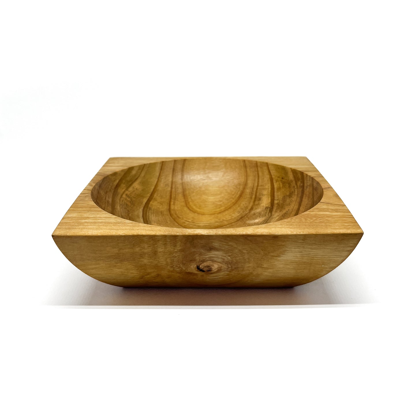 A round wooden bowl with visible grain, set within a square wooden base. The bowl has a smooth, carved interior.