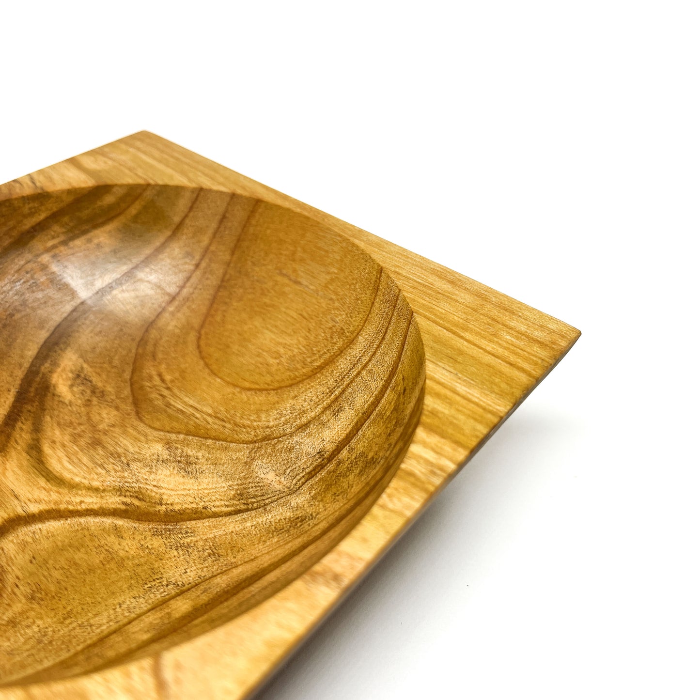 A close-up of a round wooden bowl with visible grain, set within a square wooden base. The bowl has a smooth, carved interior.