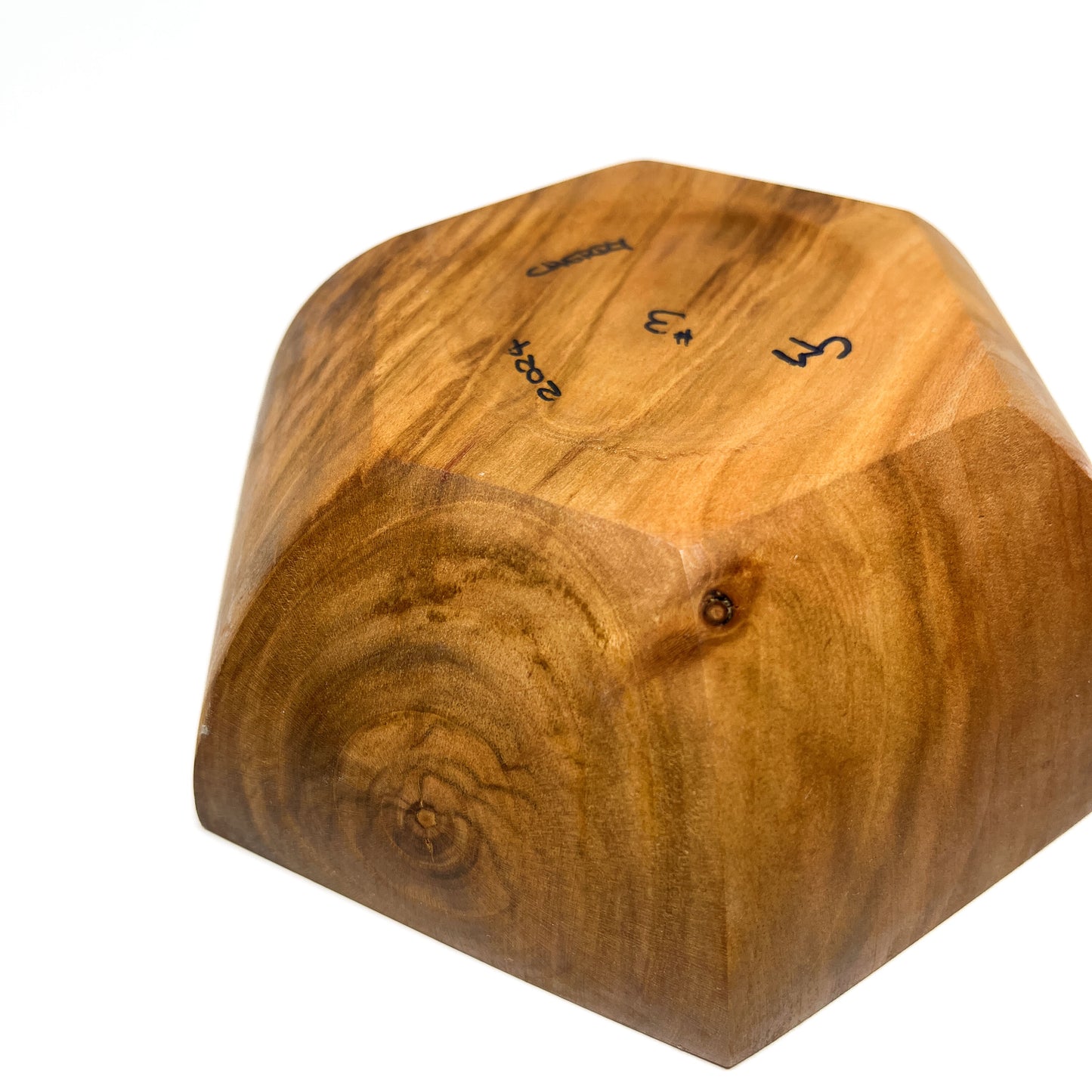 A close-up of the bottom of a six-sided wooden bowl, showing markings.