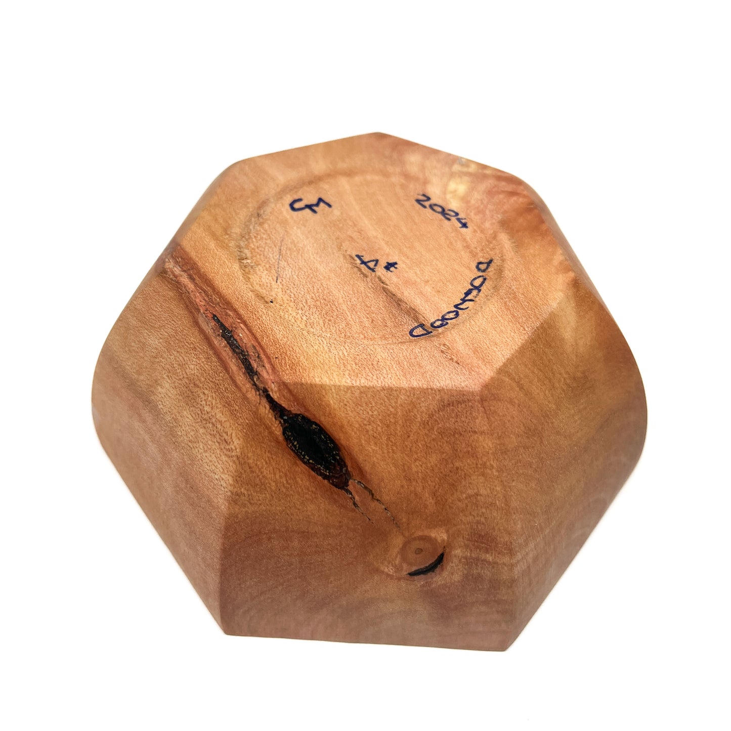 A close-up of the bottom of a light-colored, eight-sided wooden bowl with markings.