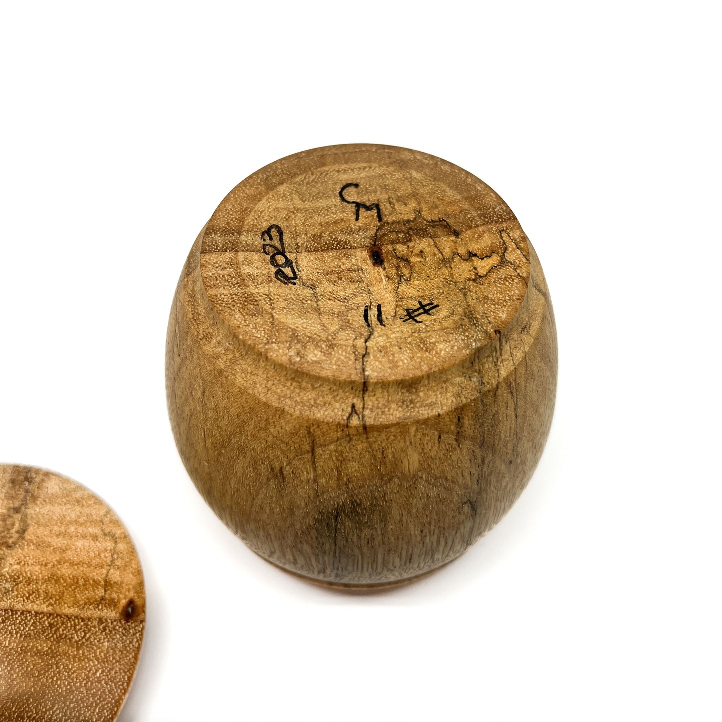 Bottom view of a hand-turned wooden pot with maker's marks and the year '2023' inscribed.