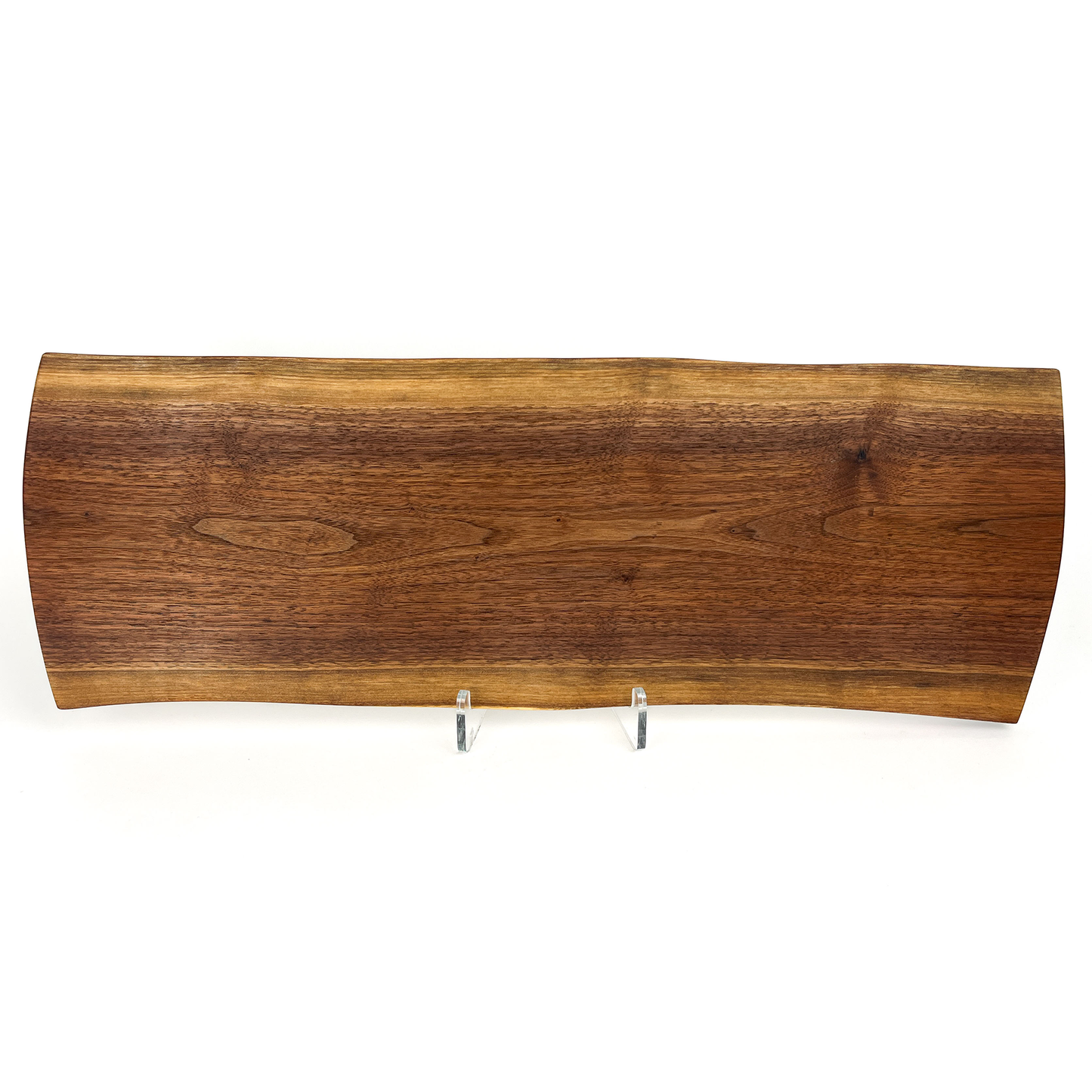 Live edge wooden charcuterie board with natural wood grain, displayed on clear risers.