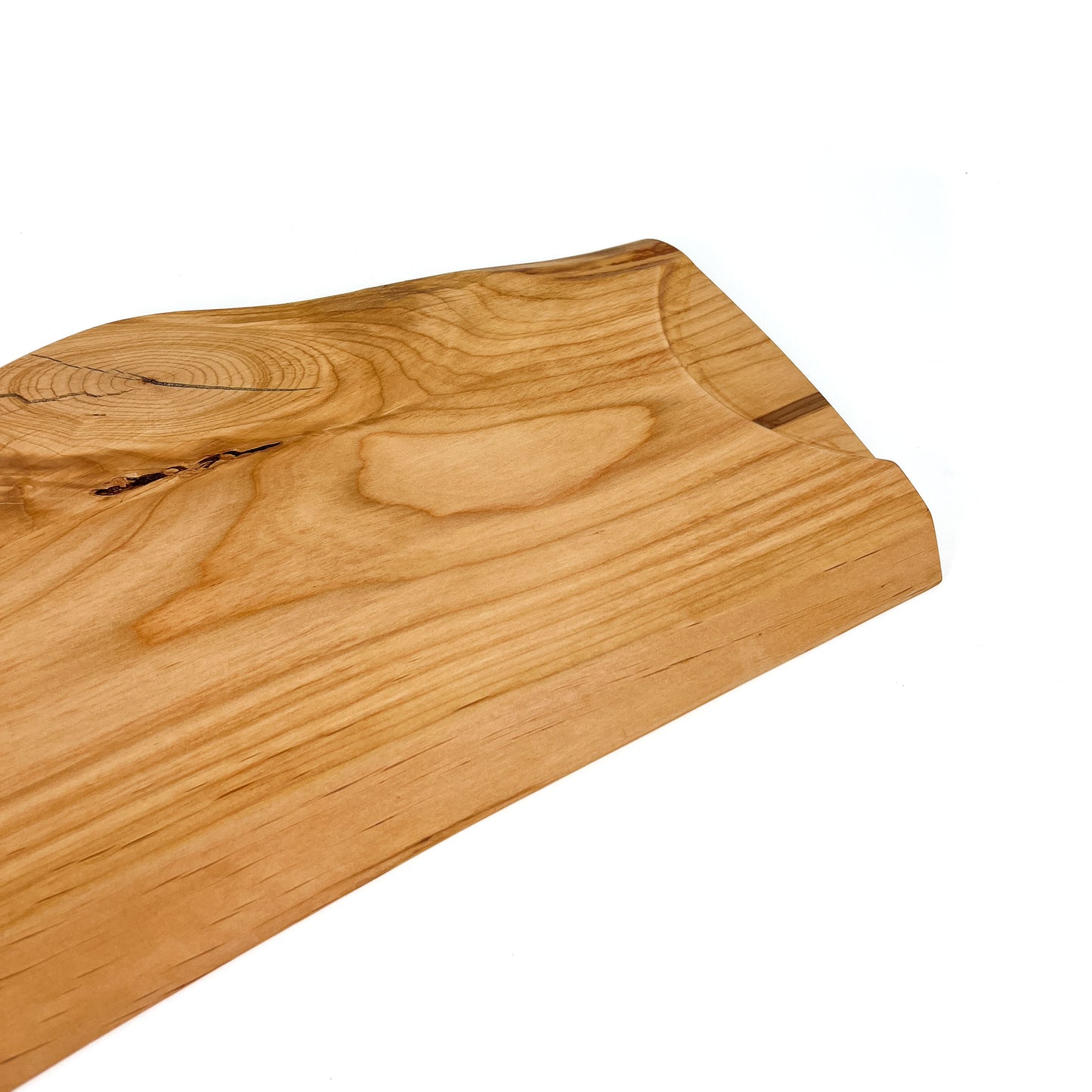 Angled close-up of a live edge wooden board with natural grain and a slight curve.