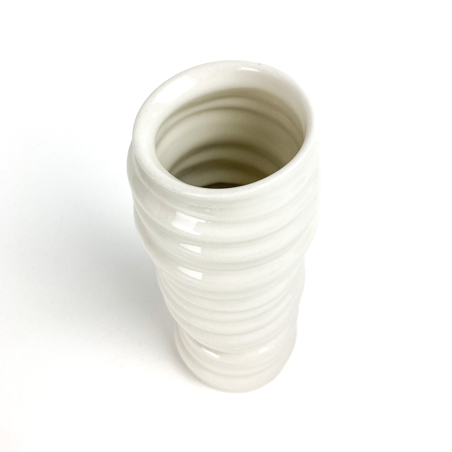 Top-down view of a cylindrical ceramic vase with horizontal ridges, showing its hollow interior and slightly curved form.