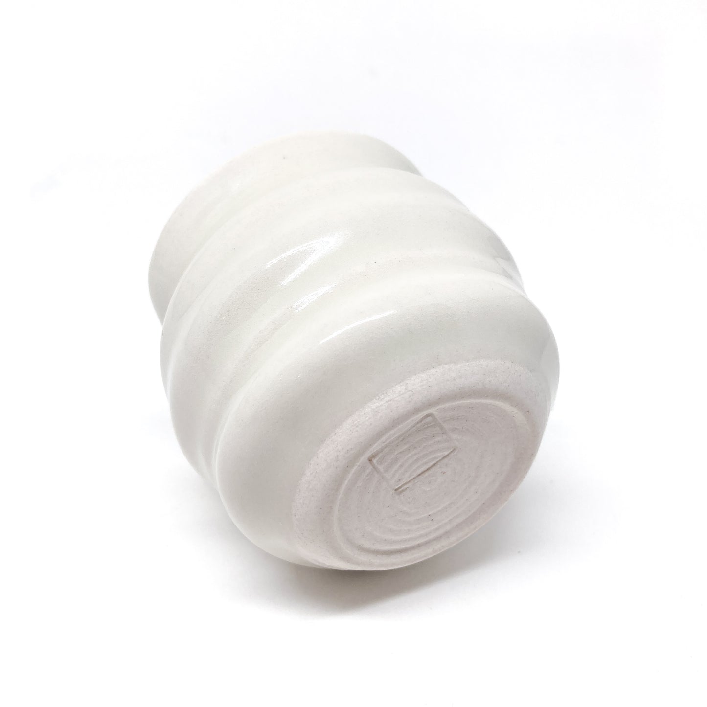 Bottom view of a small ceramic creamer with horizontal ridges and a pointed spout, showing a rectangular mark on the base.