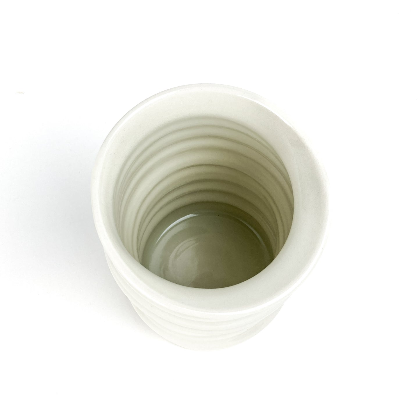 Top-down view of a small ceramic Yunomi cup with horizontal ridges, showing its smooth, hollow interior.