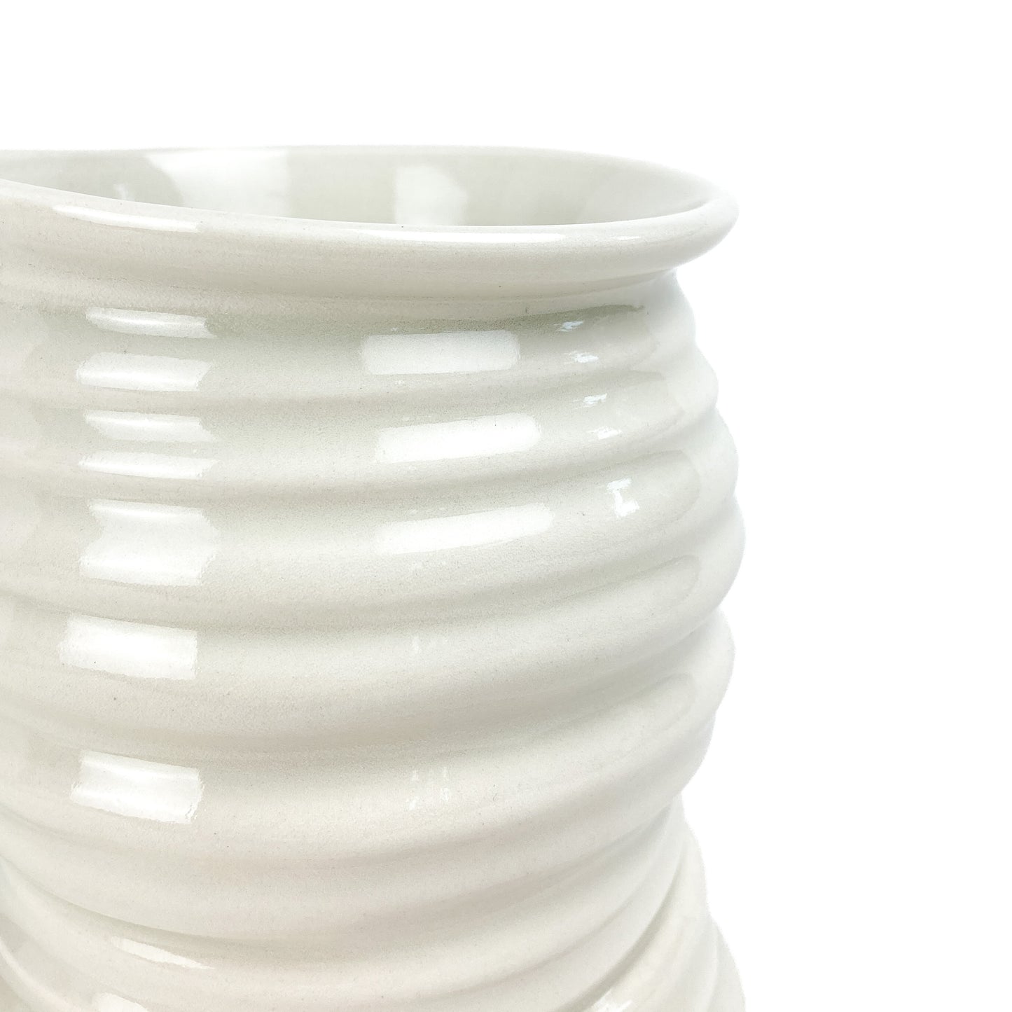 Close-up of a ceramic Yunomi cup showing its smooth, slightly flared rim and the textured horizontal ridges on its side.