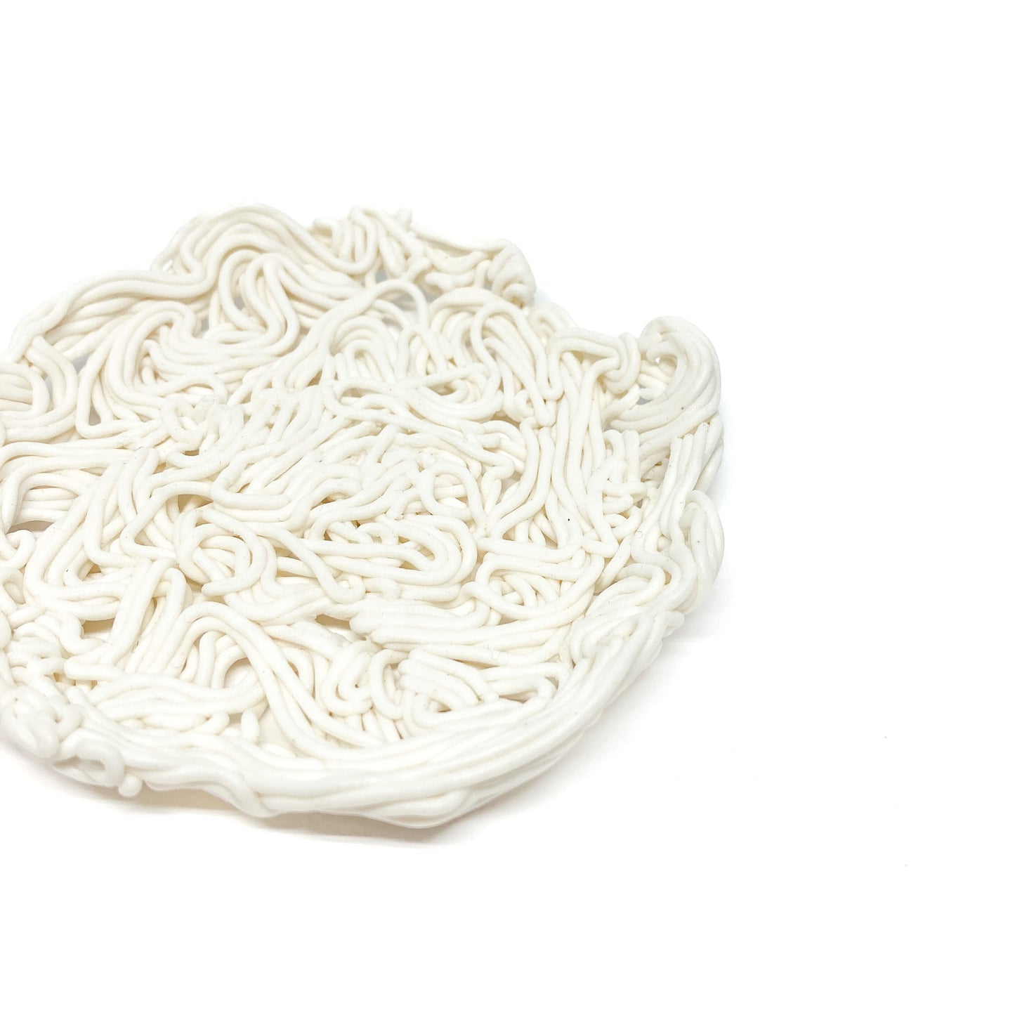 Close-up of a round ceramic spiral tealight holder with a dense, tangled, noodle-like texture.