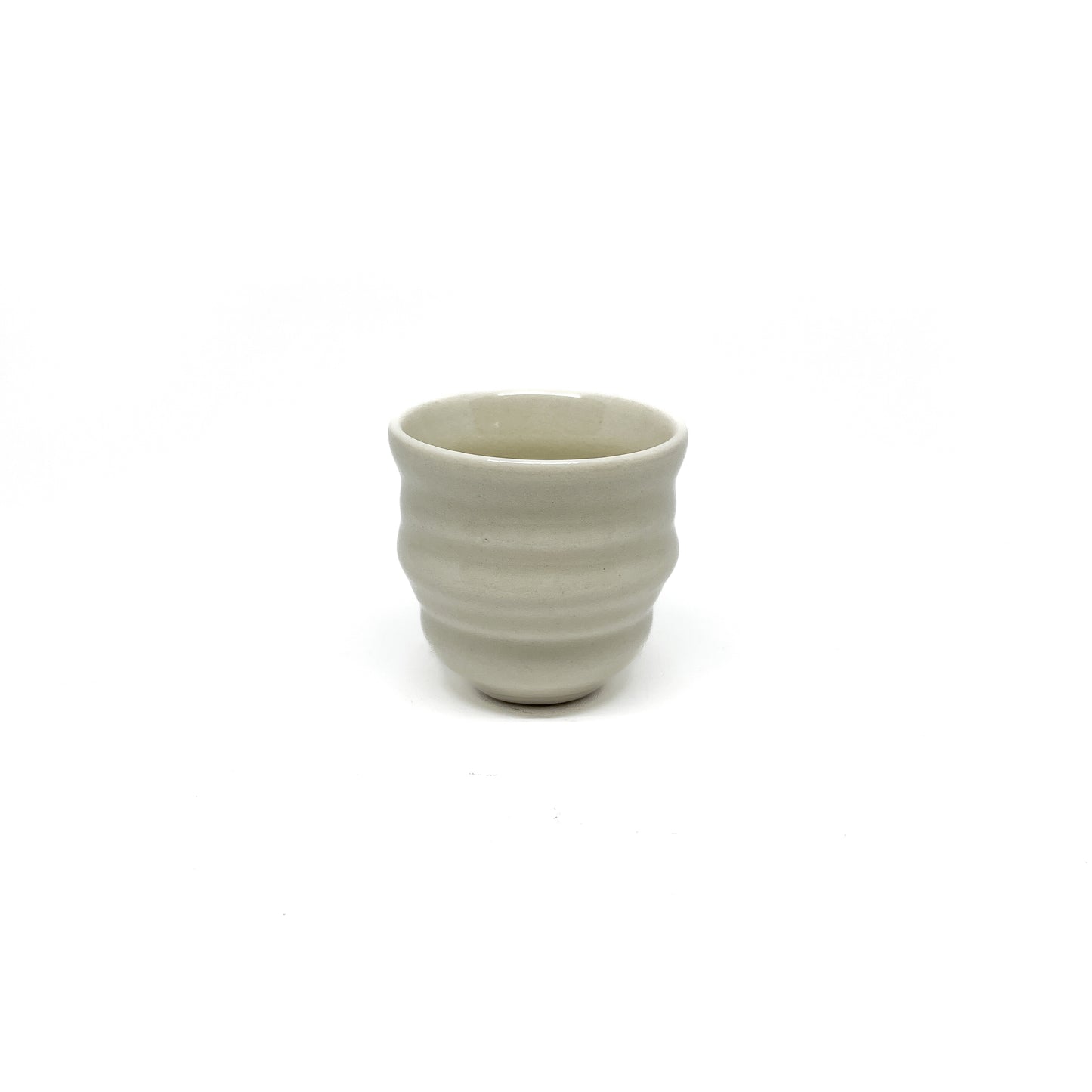 A small, round ceramic teacup with subtle horizontal ridges around its body.