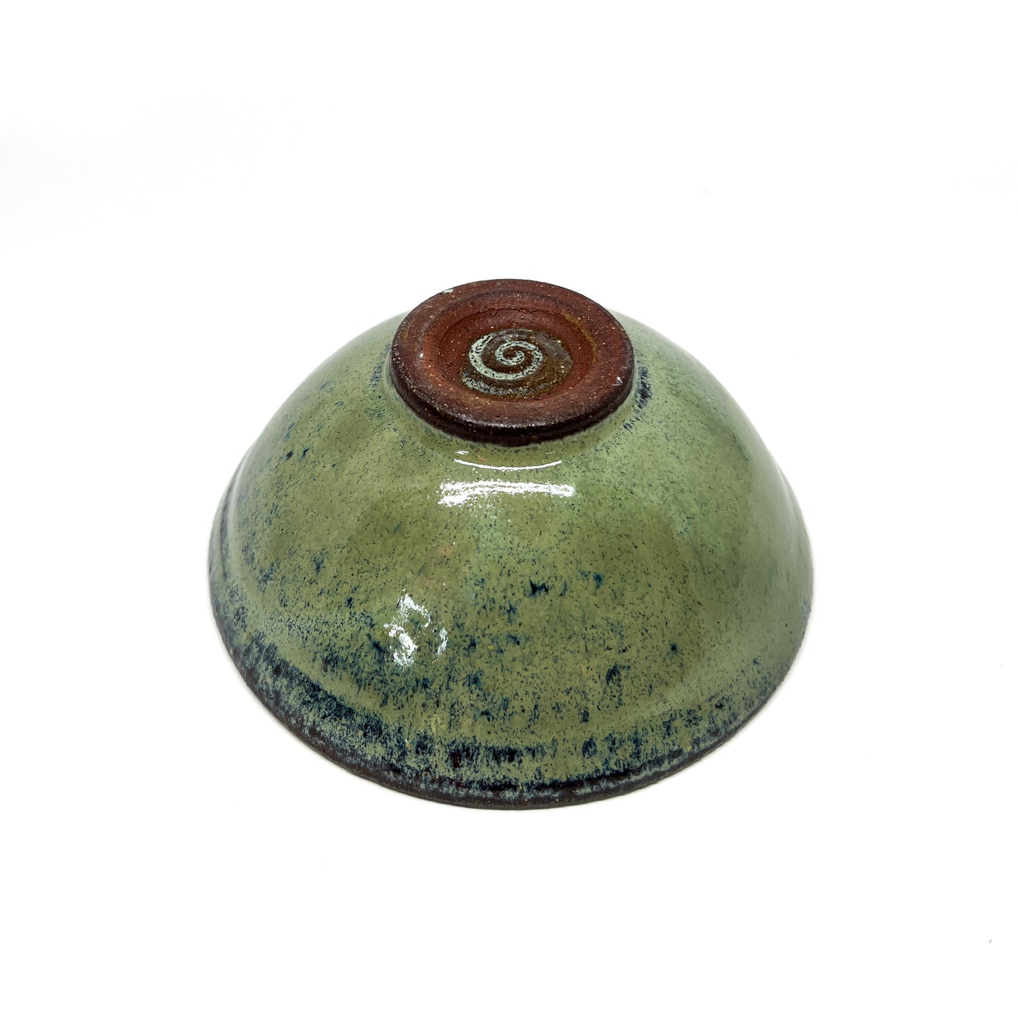 Underside of a green glazed terracotta bowl with a dark brown foot ring.