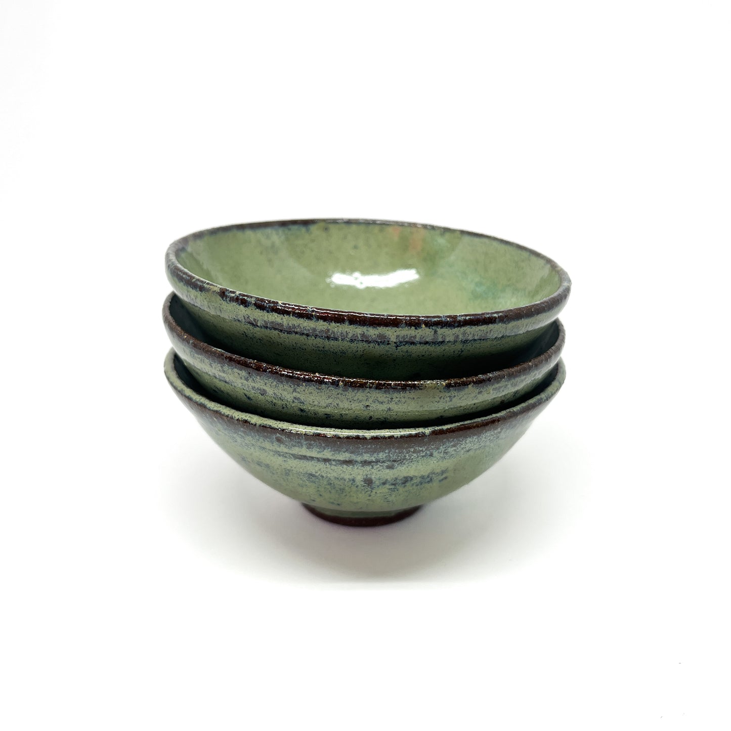 Stack of three green glazed terracotta bowls with dark rims.