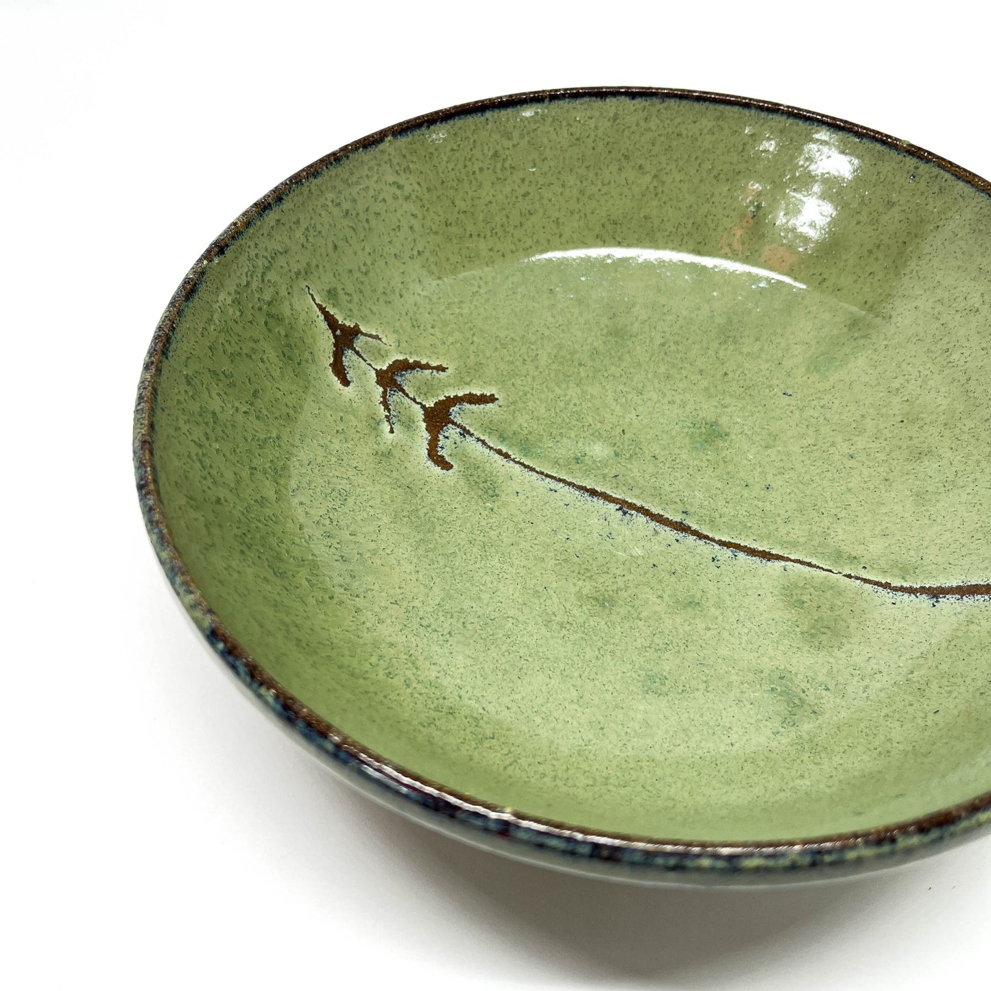 Green glazed terracotta bowl with a tree design, angled view on a white background.