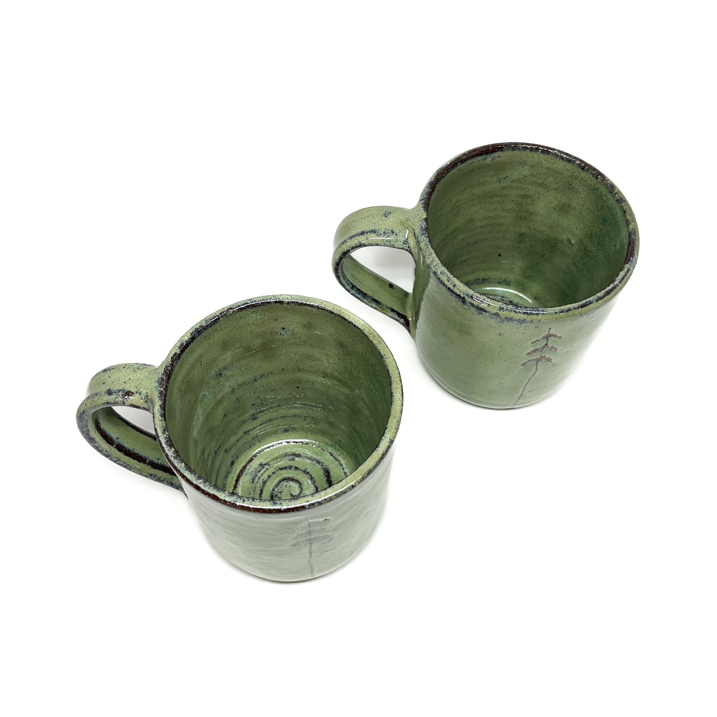 Two green ceramic mugs with tree designs, top-down view.