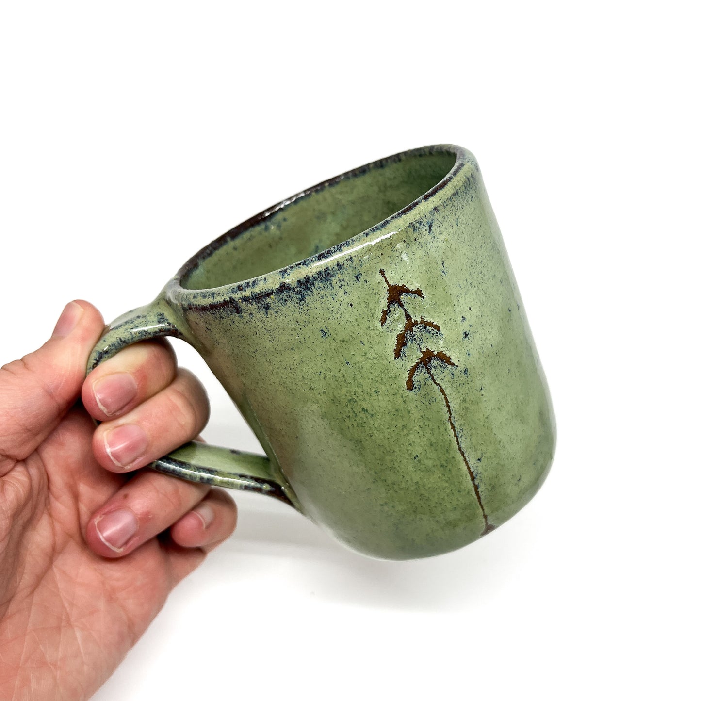One green ceramic mugs with tree design.