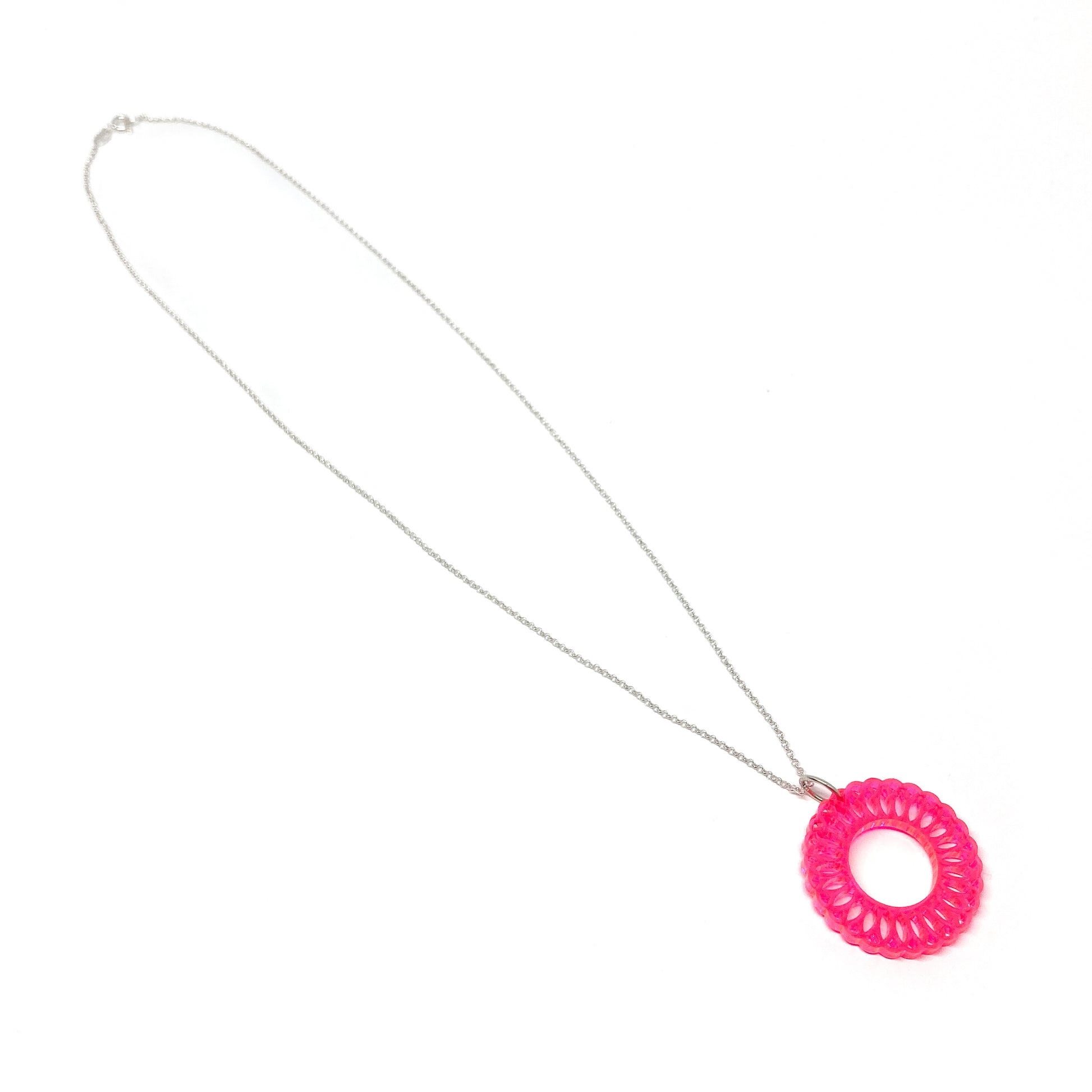 A silver chain necklace with a translucent pink circular pendant featuring an intricate, layered geometric design and a central open circle.