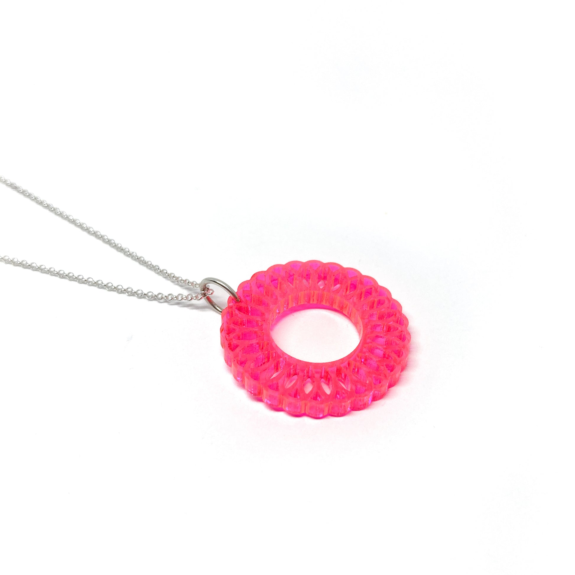 A silver chain necklace with a translucent pink circular pendant featuring an intricate, layered geometric design and a central open circle.
