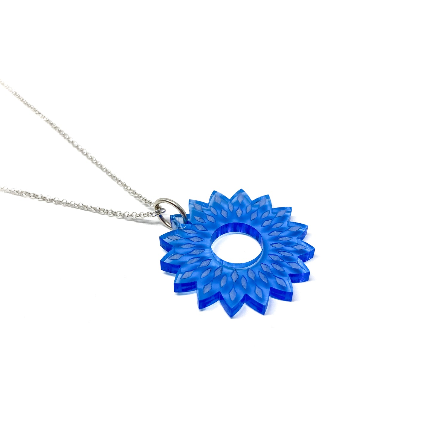 A silver necklace featuring a translucent blue mandala pendant with a stylized floral and geometric design and a central open circle.
