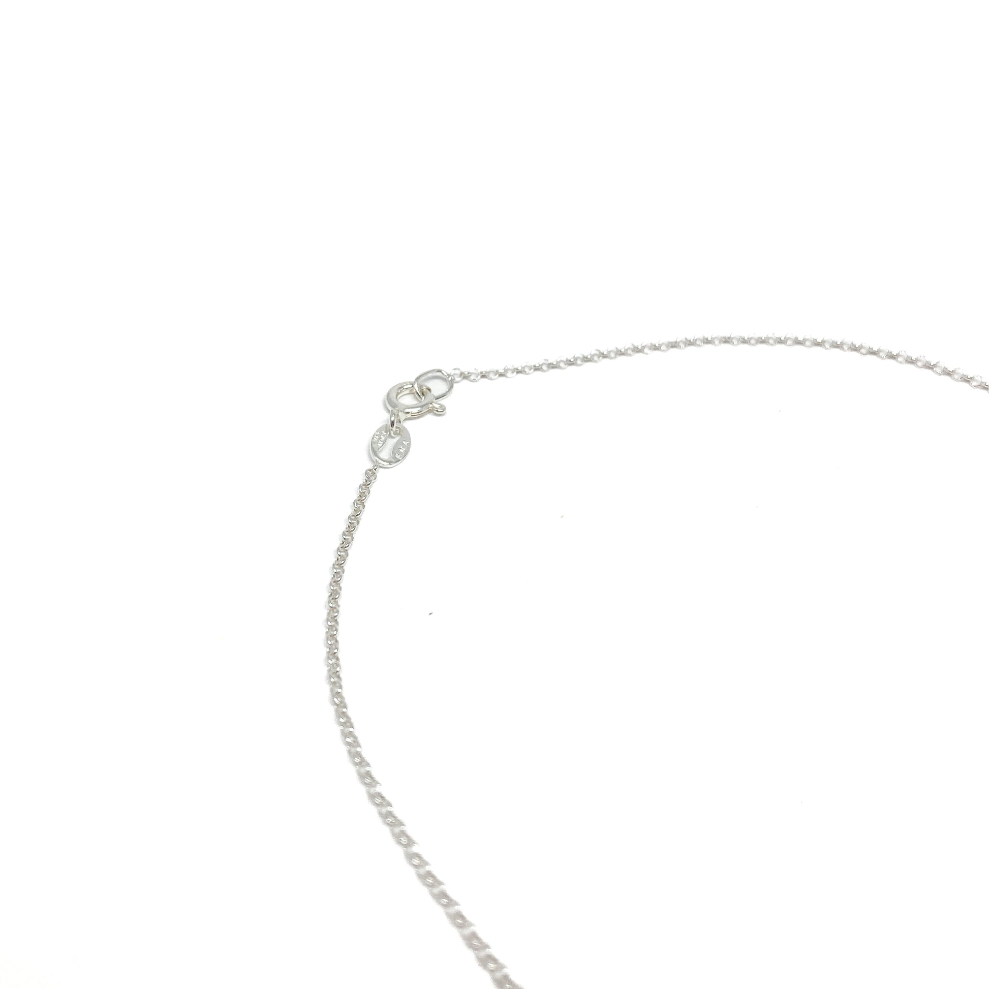 A close-up of the silver toggle clasp and delicate chain of a necklace, showing the fastening mechanism.