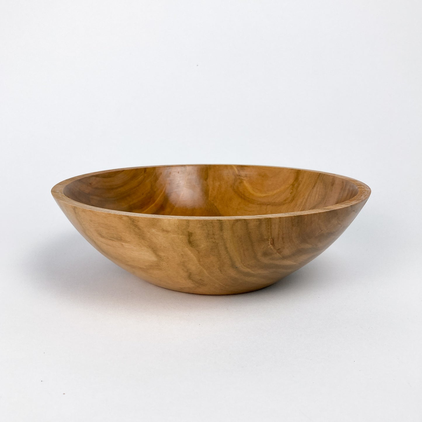 A wooden bowl with a smooth, polished finish, showing natural wood grain.