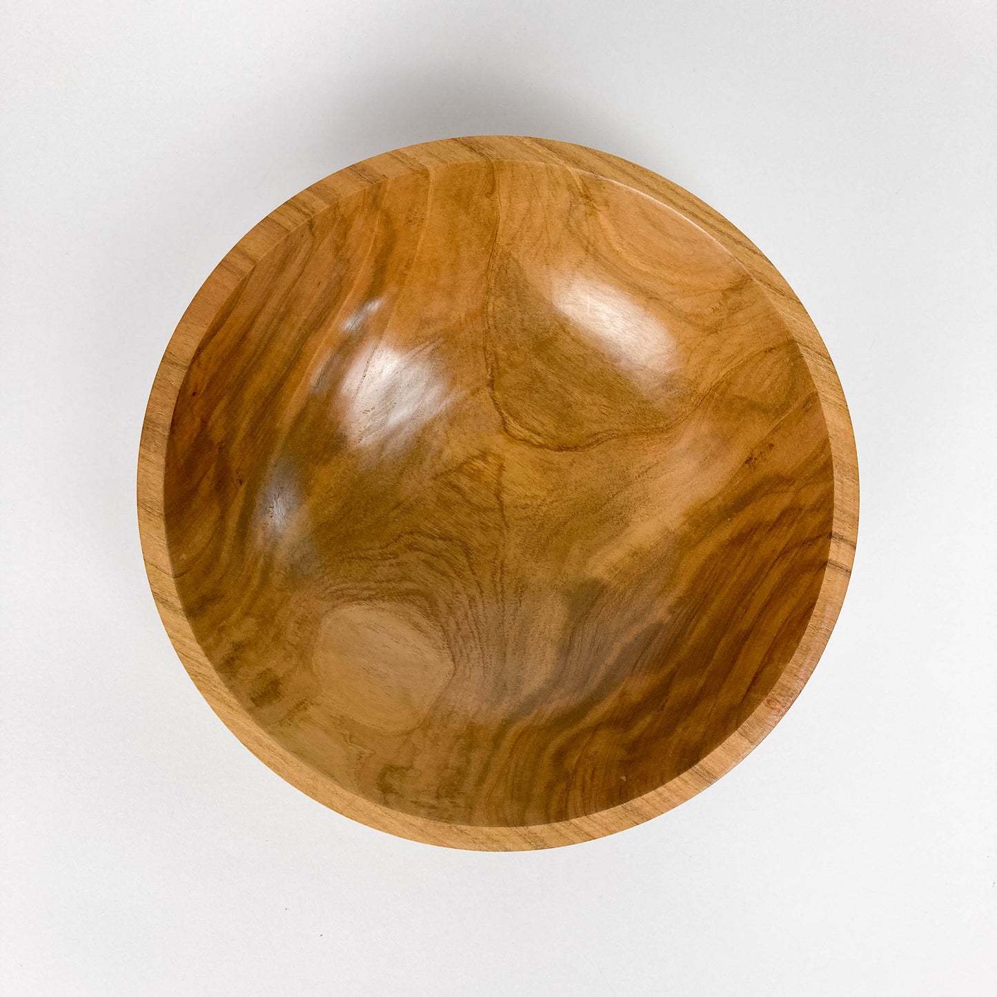 A wooden bowl with a smooth, polished finish, viewed from above, showing natural wood grain patterns.