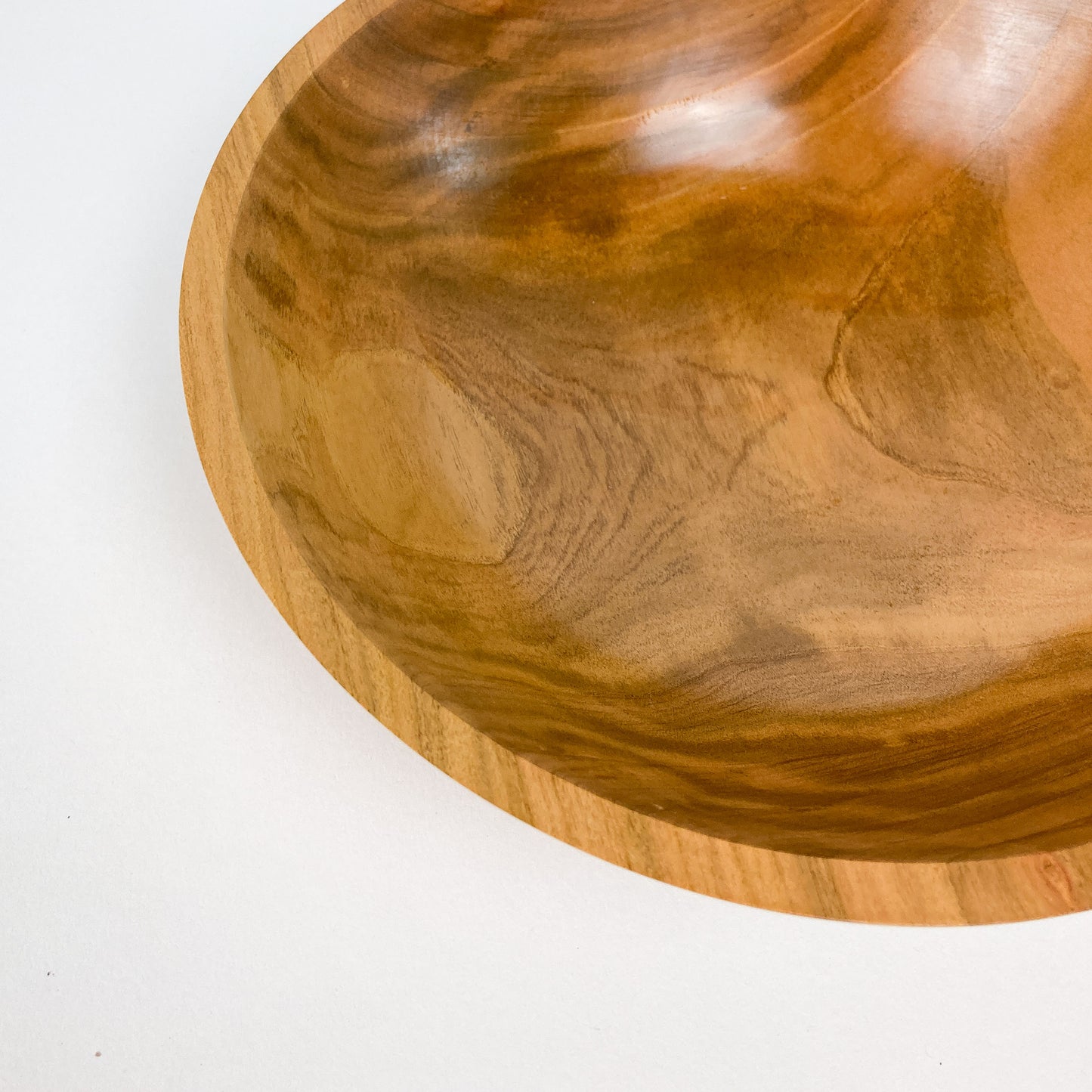 A close-up view of a wooden bowl, showing the smooth, polished finish and natural wood grain patterns.