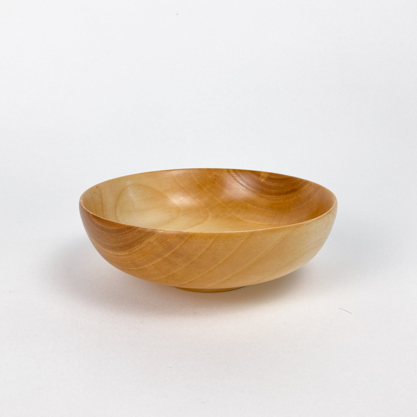 Side view of a smooth, light-colored wooden Cherry Candy Bowl with visible grain.