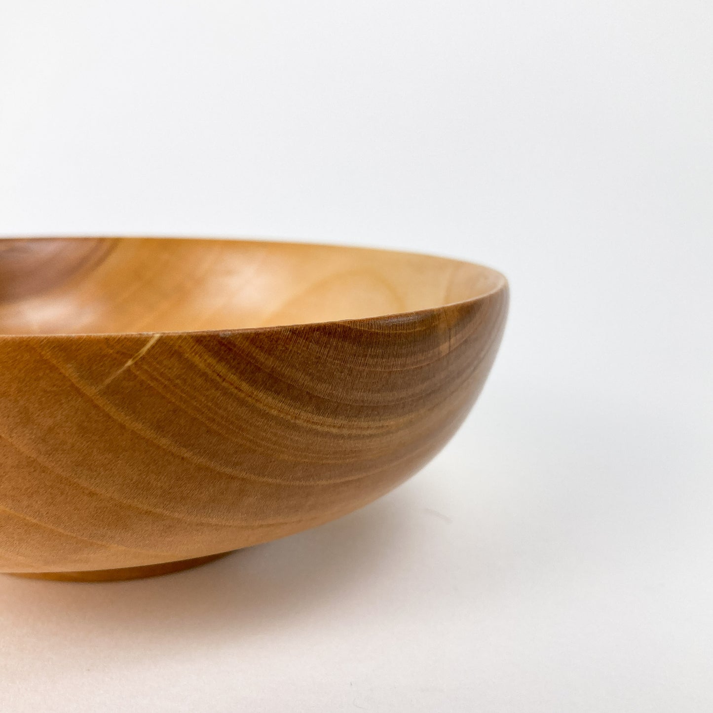 Close-up side view of a smooth, light brown wooden Cherry Candy Bowl, showcasing its rim and grain.
