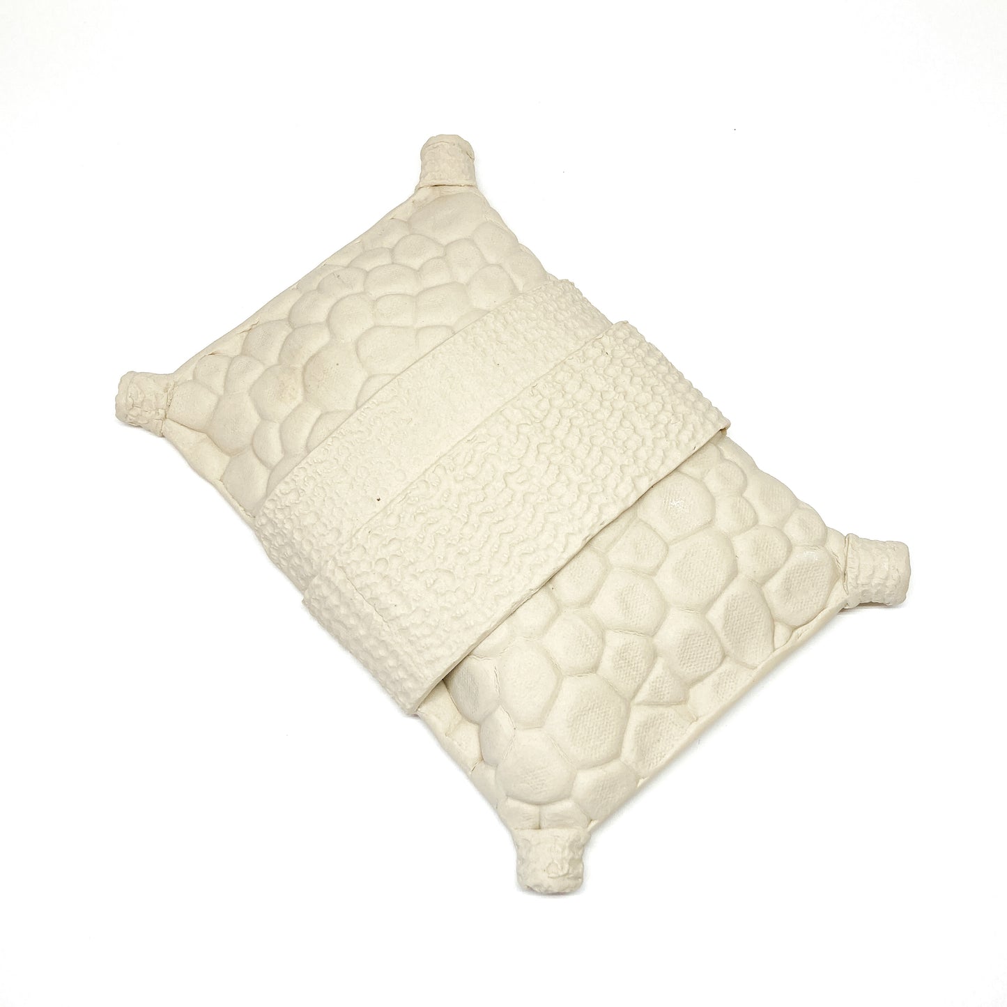 Textured, diamond-shaped pillow wall sculpture with a band across the middle and cylindrical forms at each corner.