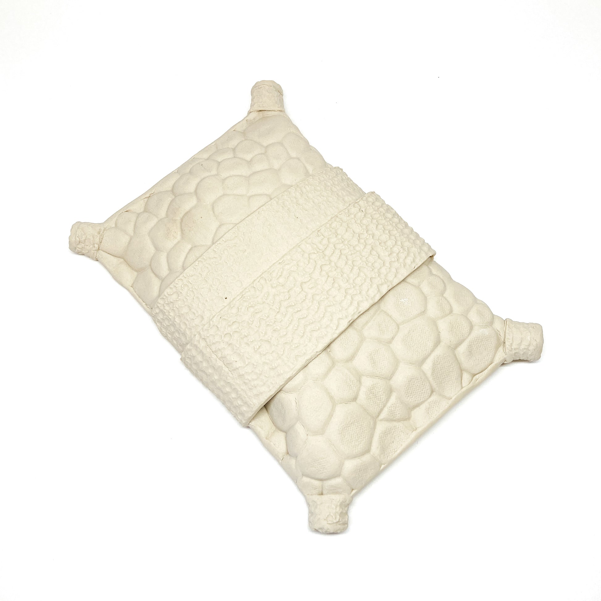 Textured, diamond-shaped pillow wall sculpture with a band across the middle and cylindrical forms at each corner.