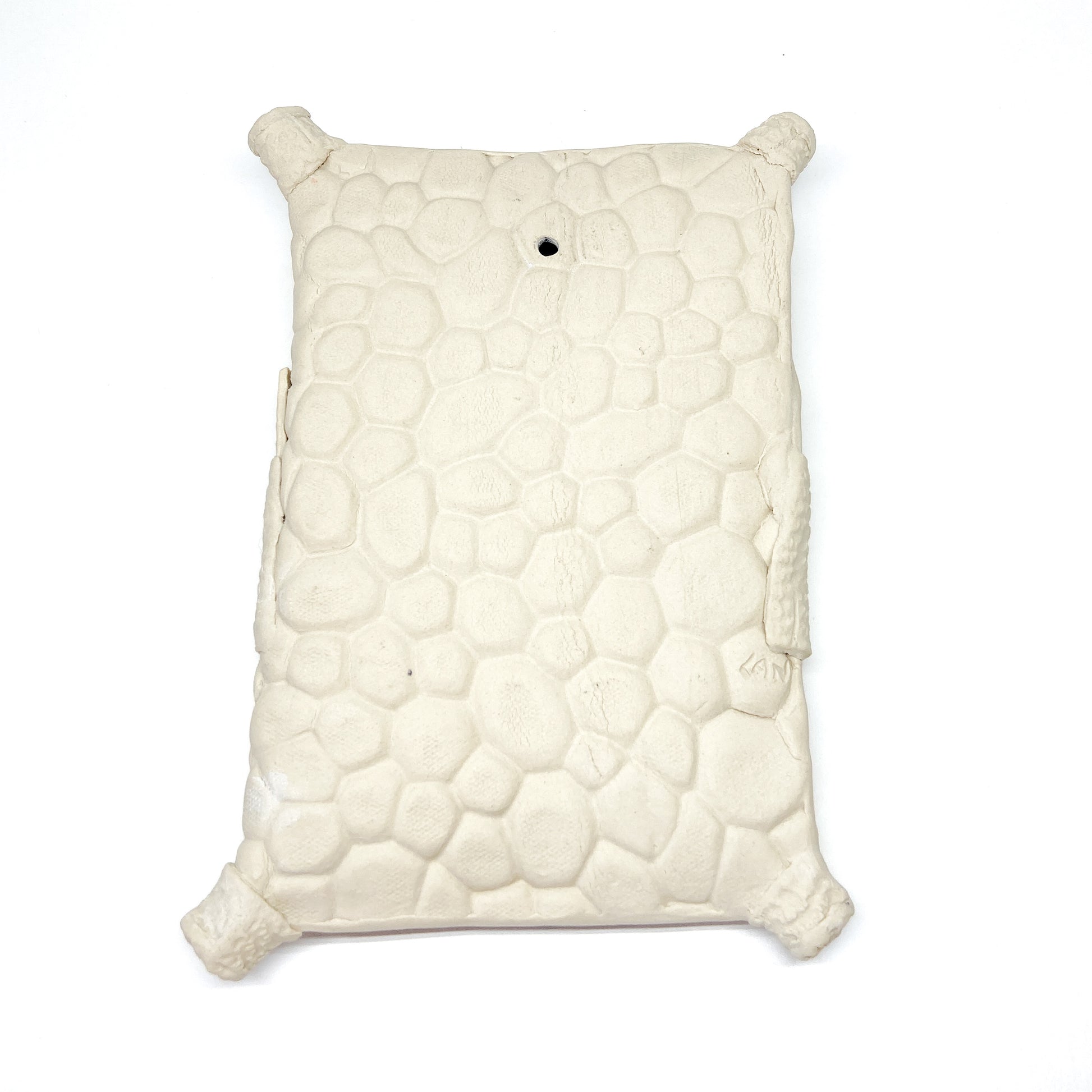 Textured, pillow-shaped wall sculpture with rounded corners and a hole in the upper top.
