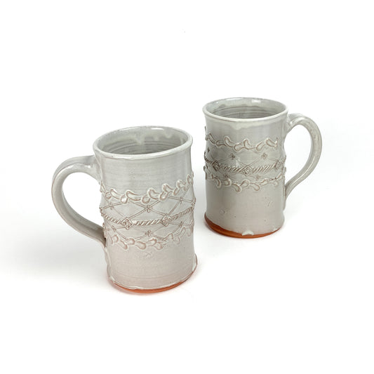 Two ceramic Coral Patola Trellis Steins with raised coral and garland designs and unglazed bases.