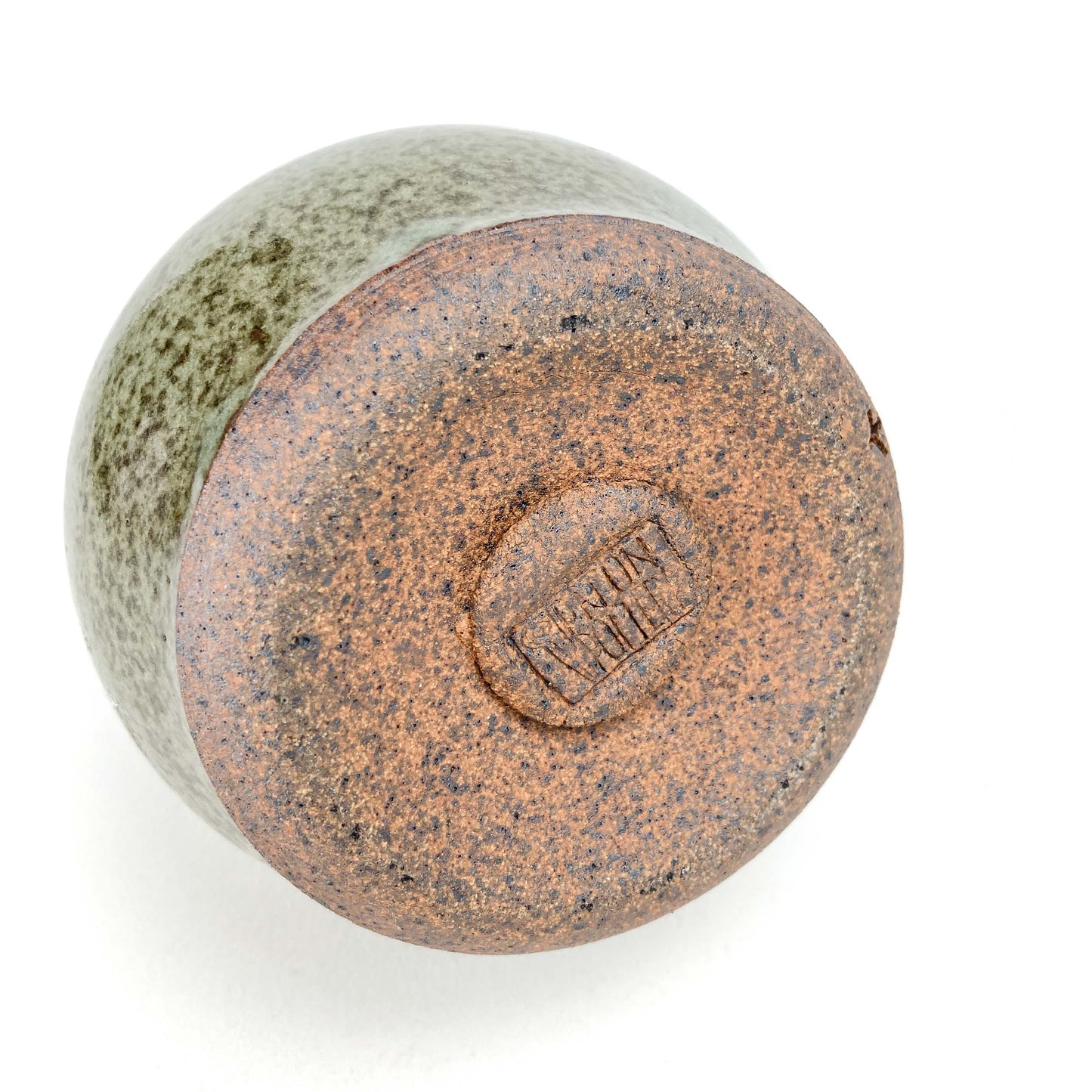 Bottom view of a Coral Patola Celadon pump bottle showing its textured, unglazed base and maker's mark.